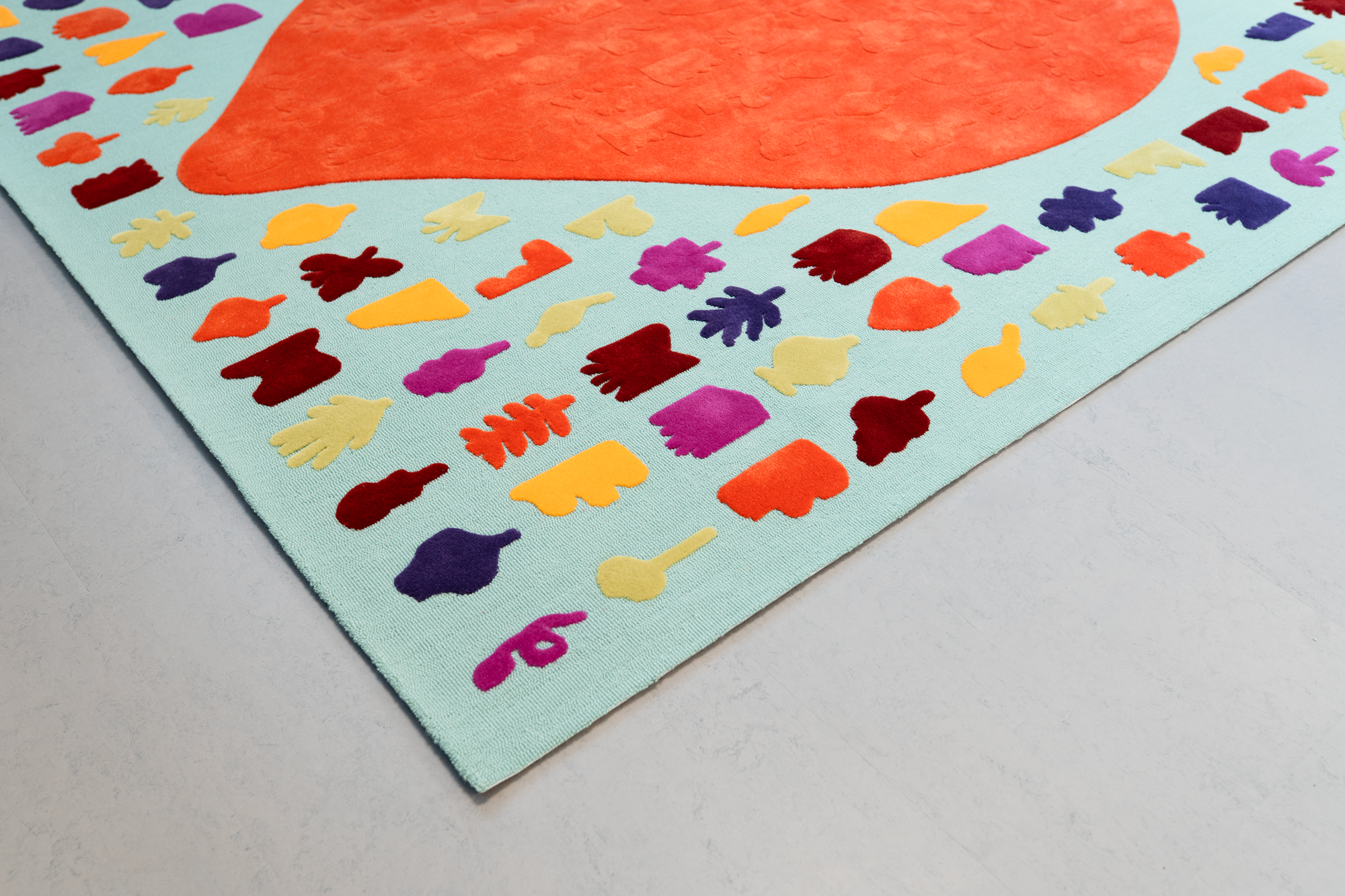 Colorful felt cutouts of various shapes with a large orange heart in the center on a light blue background.