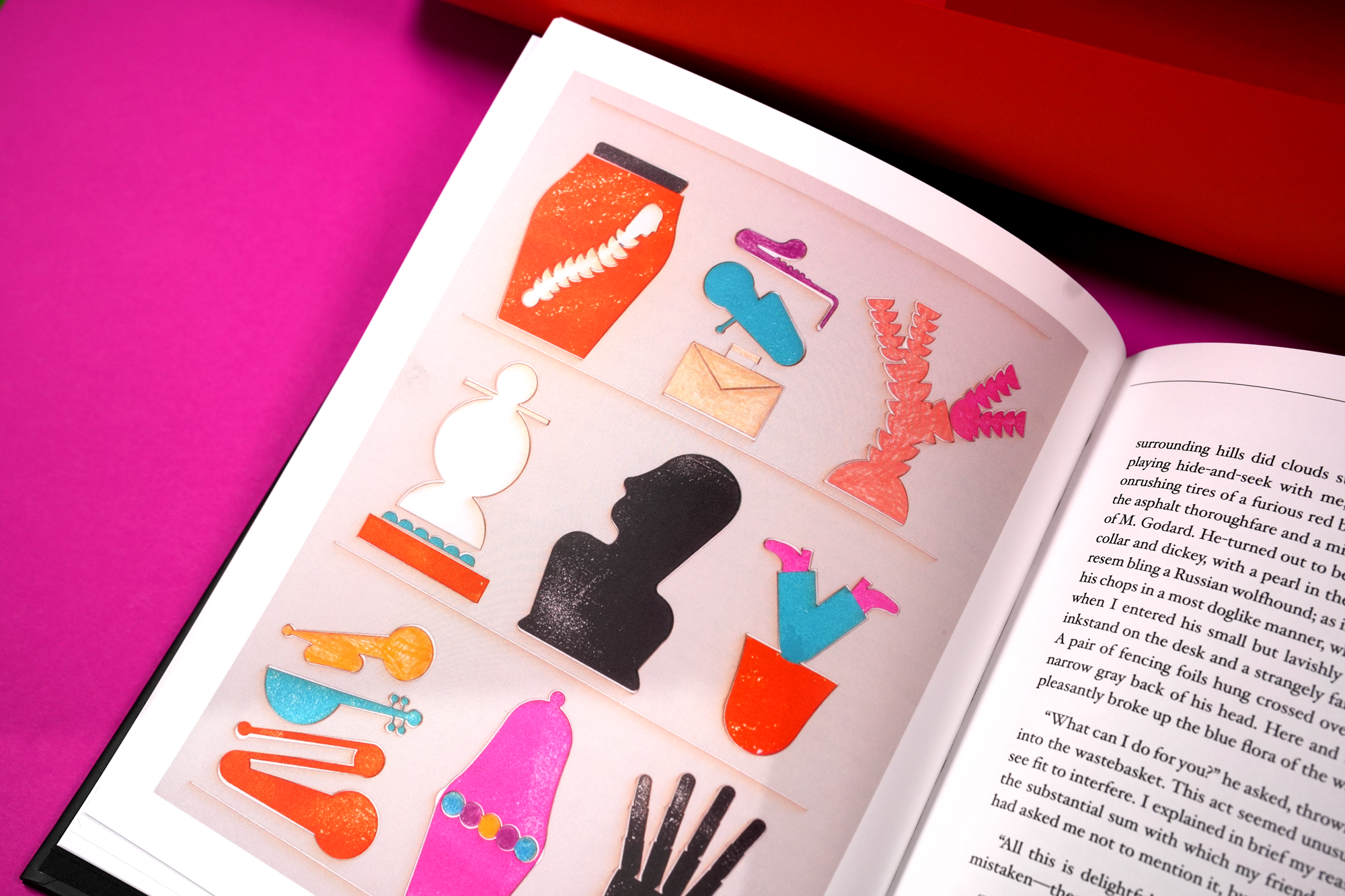 Open book with colorful stickers including a face outline, musical instruments, and a person silhouette, on a pink surface.