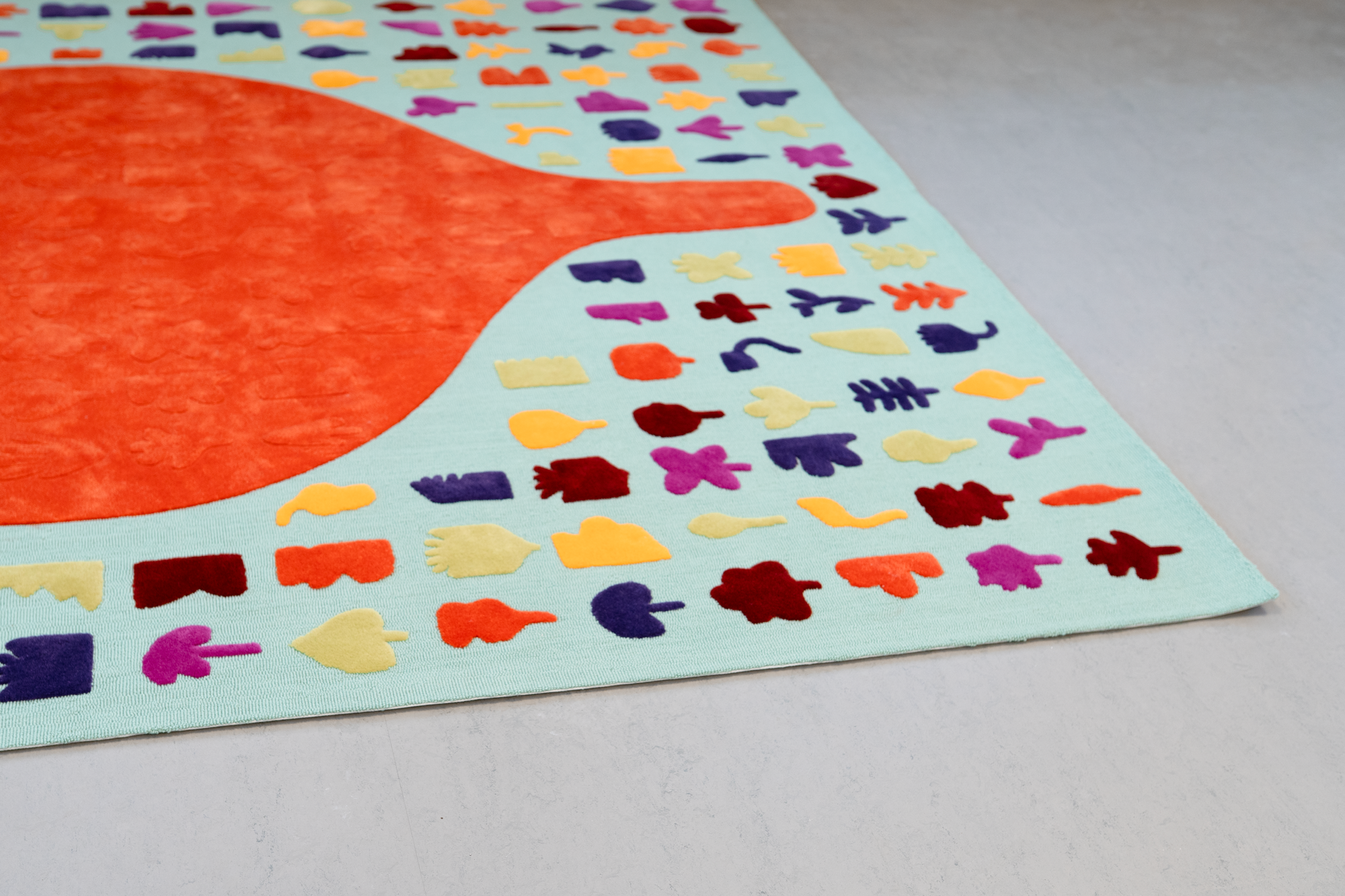 Colorful art piece with a large orange and red shape on a light blue background, surrounded by multicolored small abstract shapes or stickers.