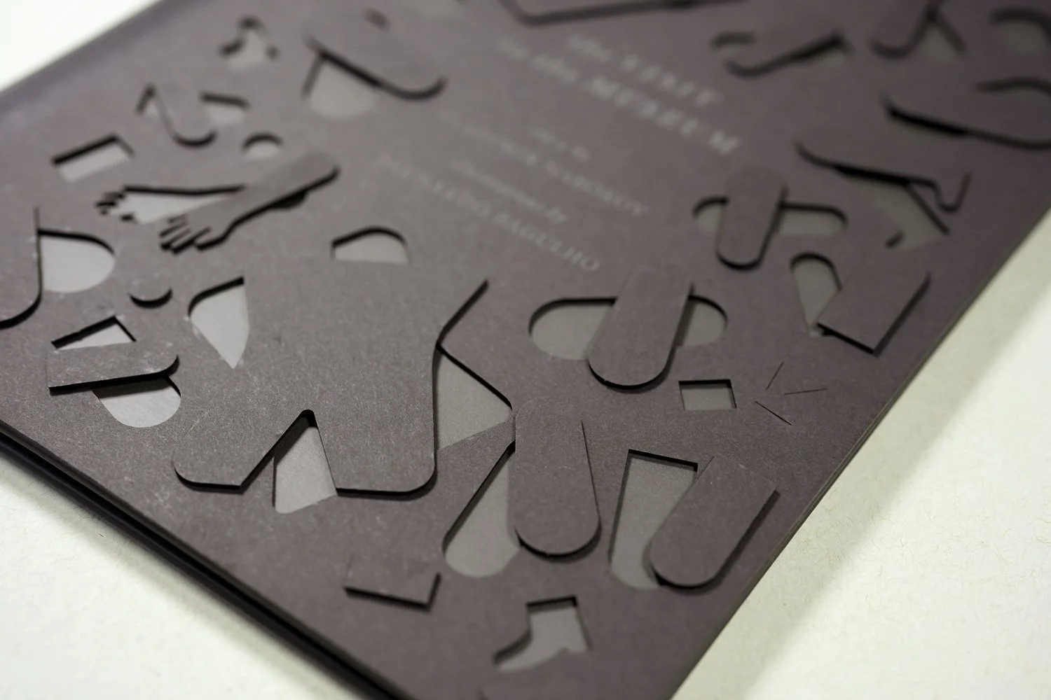 Close-up of a black greeting card with layered cut-out letters and a small illustration of a person.