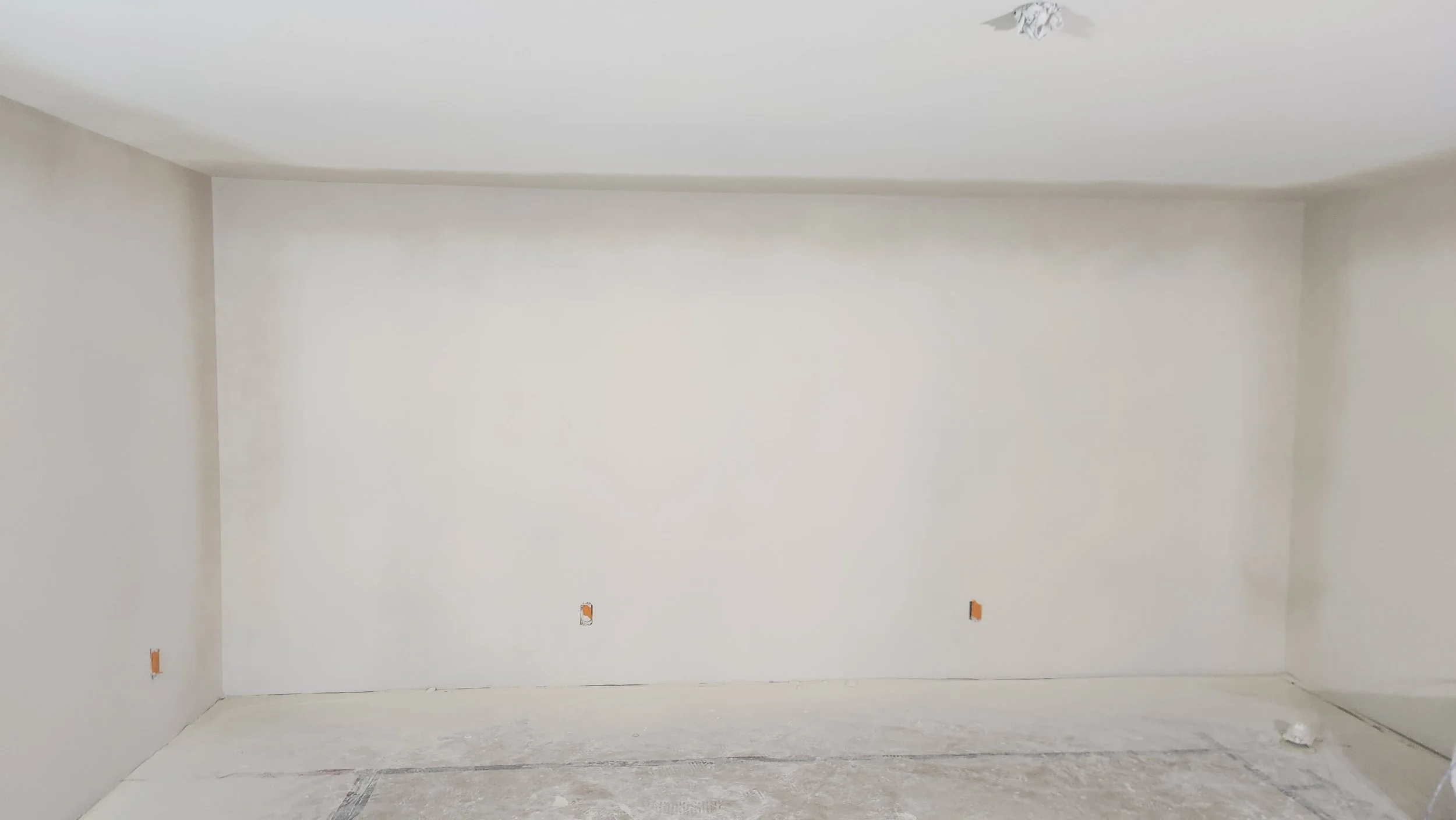 A paintbrush resting on a neatly folded white towel or cloth on a white surface with a textured white wall in the background.