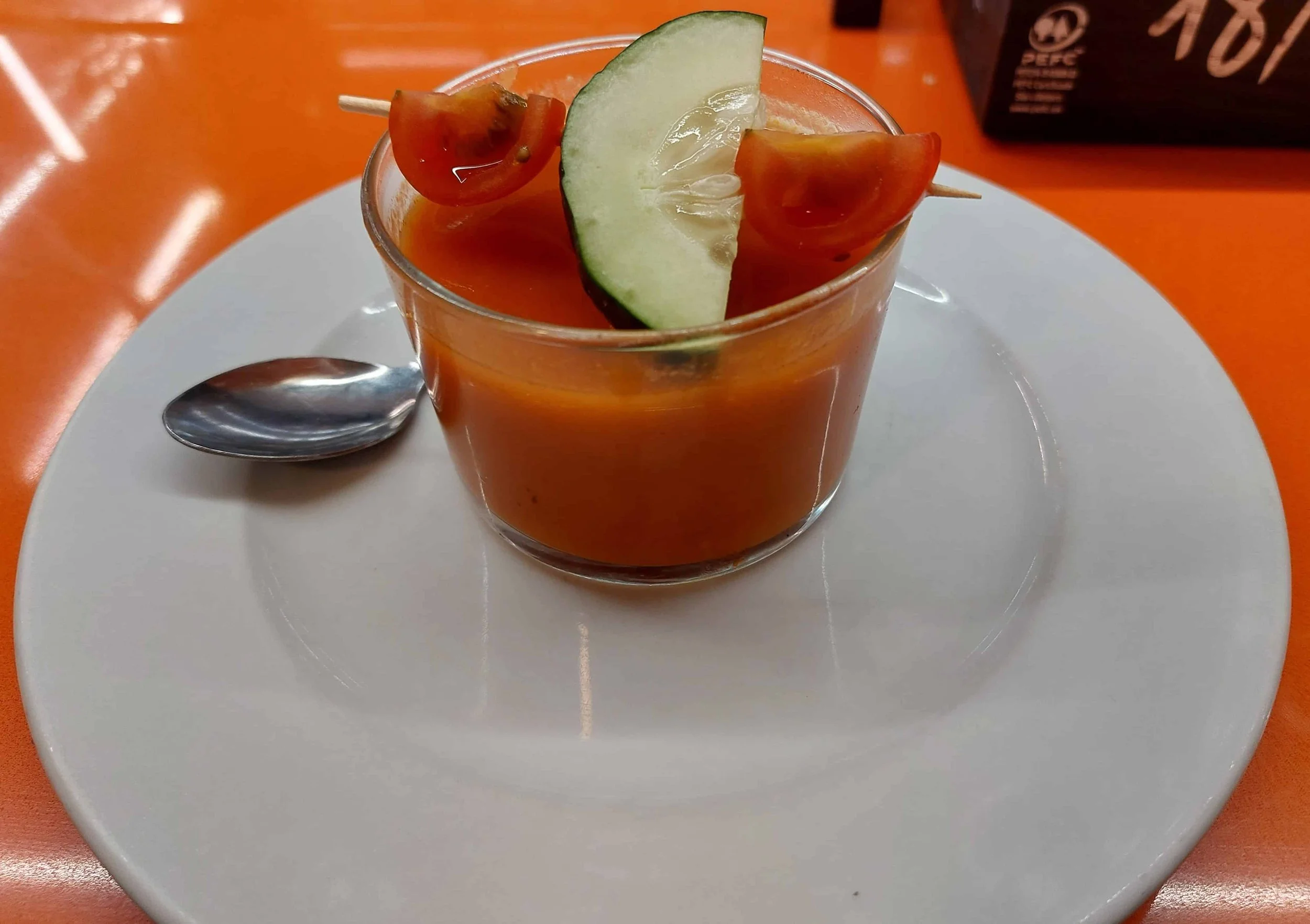 Spanish gazpacho served in small glass with cucumber and cherry tomato on toothpick