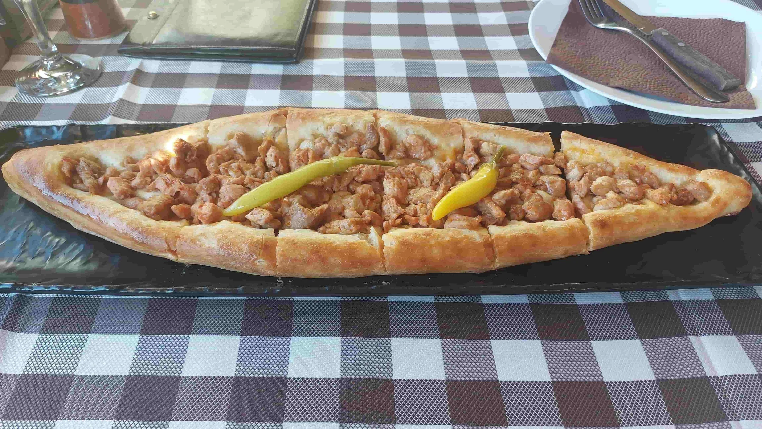 Macedonian Pastrmajlija flatbread topped with salted pork cubes, spices, and three chilies