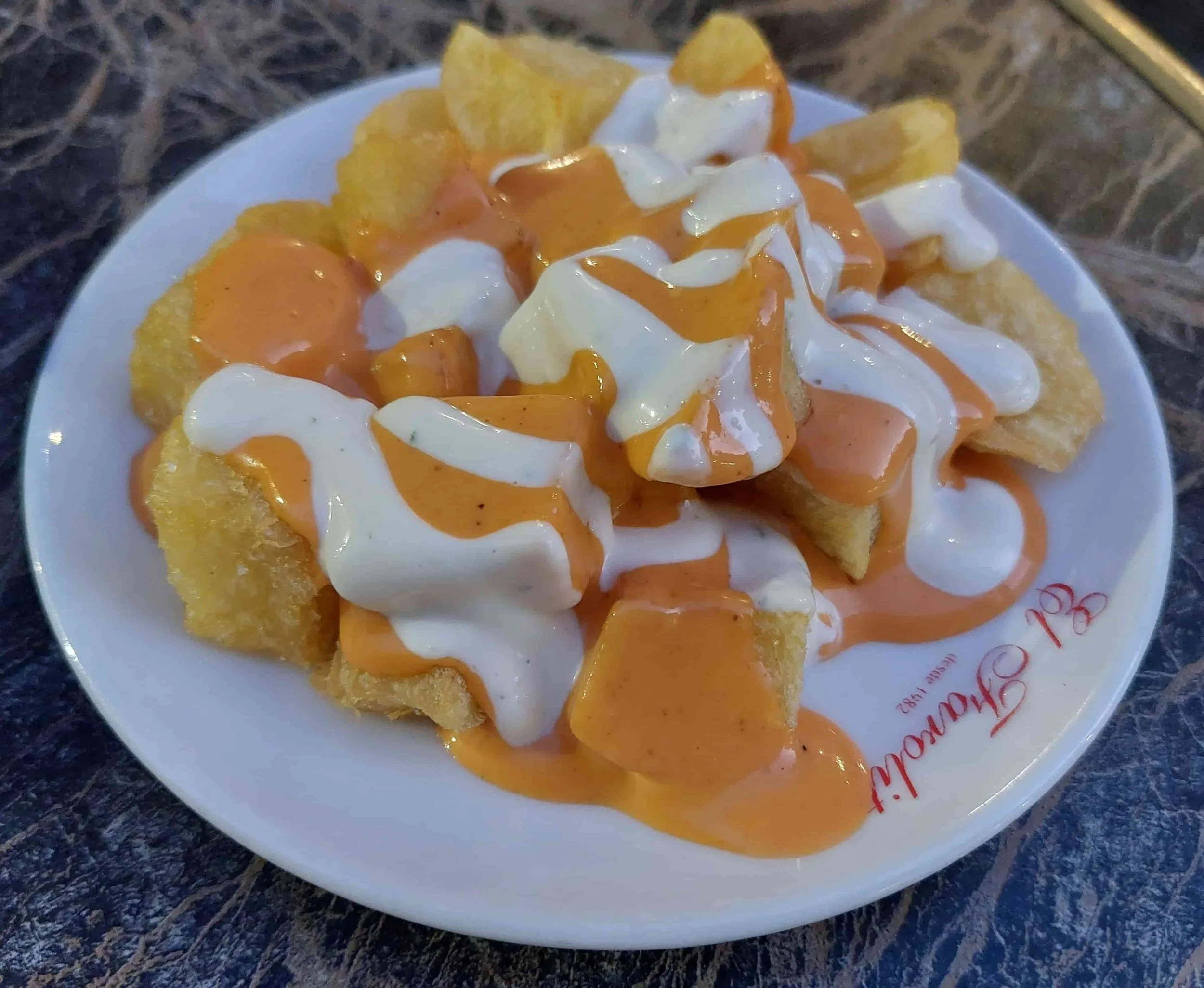Spanish Patatas Bravas fried potato cubes with spicy tomato sauce and aioli