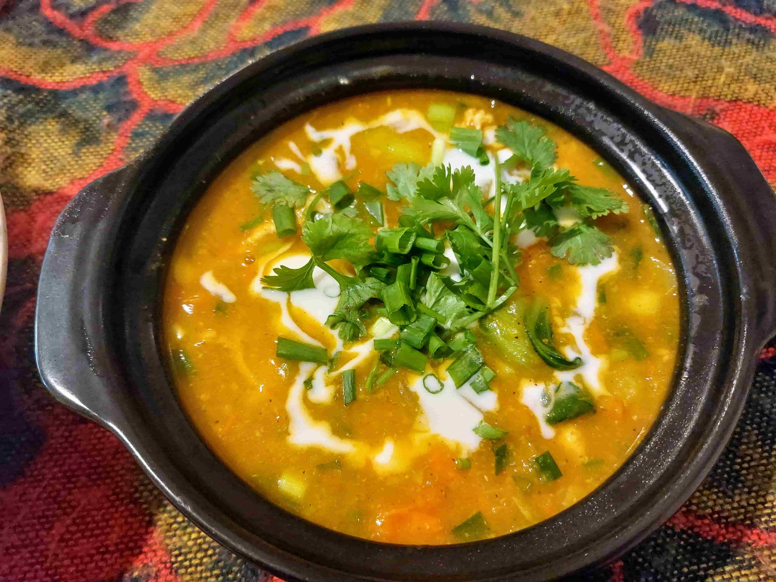 Bowl of Cà Ri Vietnamese chicken curry with root vegetables and fresh herb garnish
