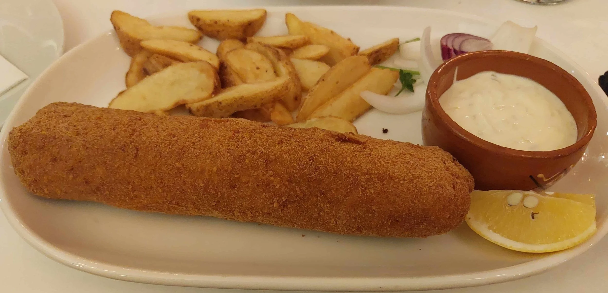 Karađorđeva šnicla, breaded rolled veal cutlet with chips, sliced onion, tartar sauce, and lemon