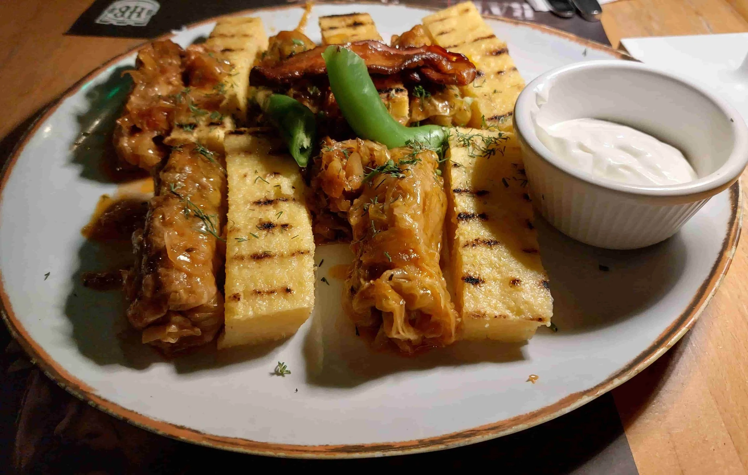 Romanian sarmale cabbage rolls with grilled mămăligă, sour cream, and chili peppers