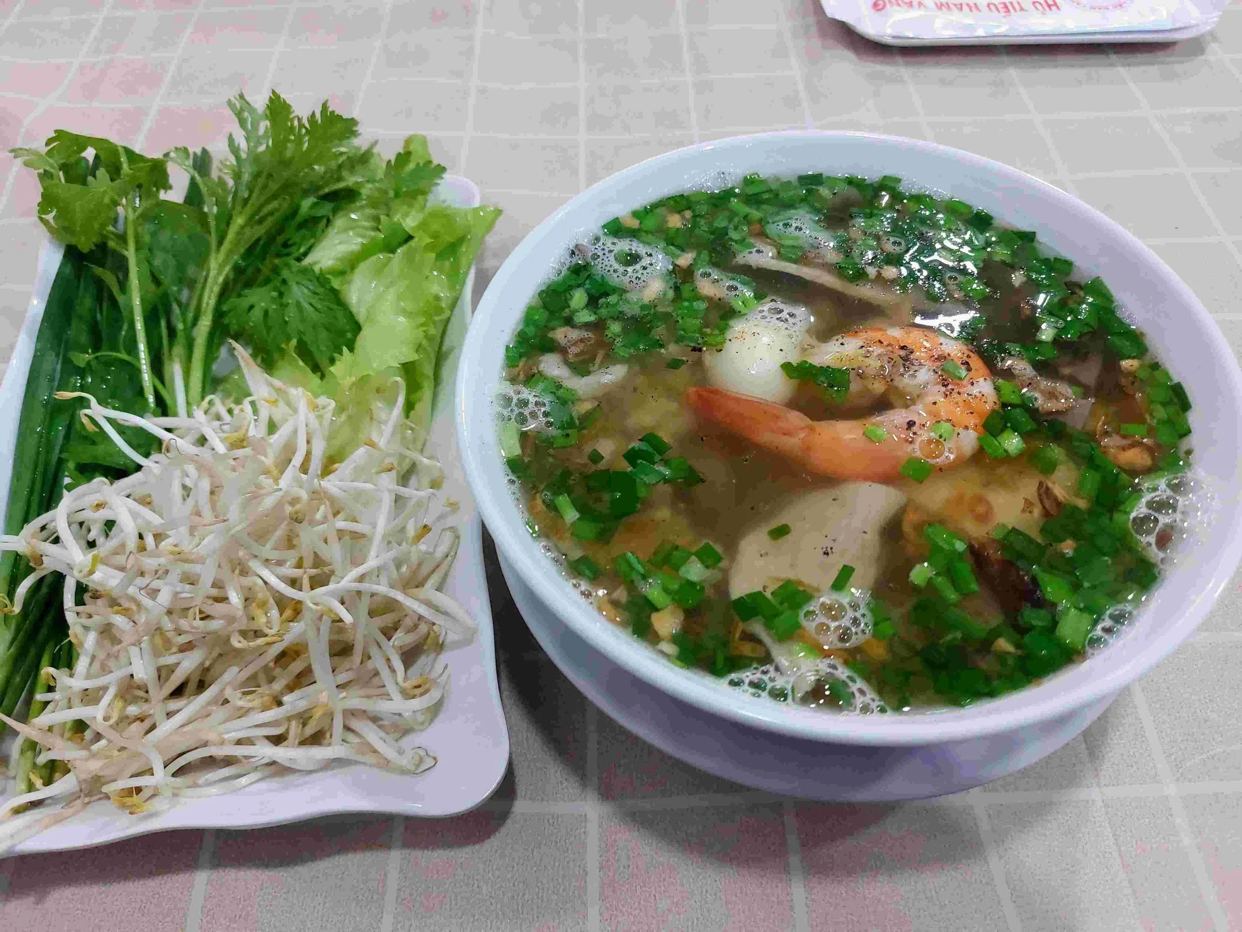 Hủ Tiếu Nam Vang – Vietnamese clear noodle soup with pork, shrimp, quail egg, served with fresh greens and bean sprouts on the side