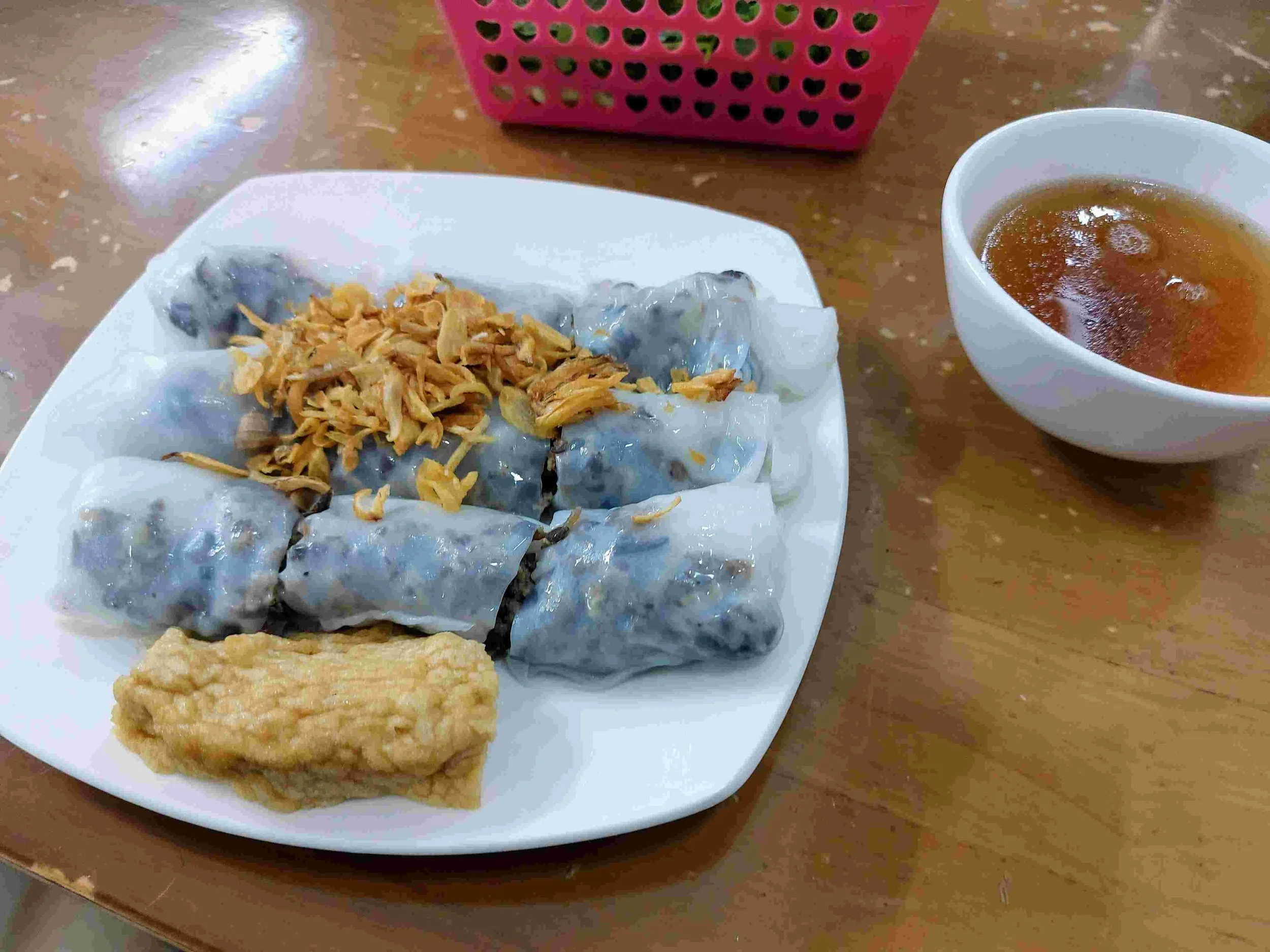 Vietnamese bánh cuốn rice rolls filled with minced pork and mushrooms, topped with fried shallots, served with tofu and dipping sauce