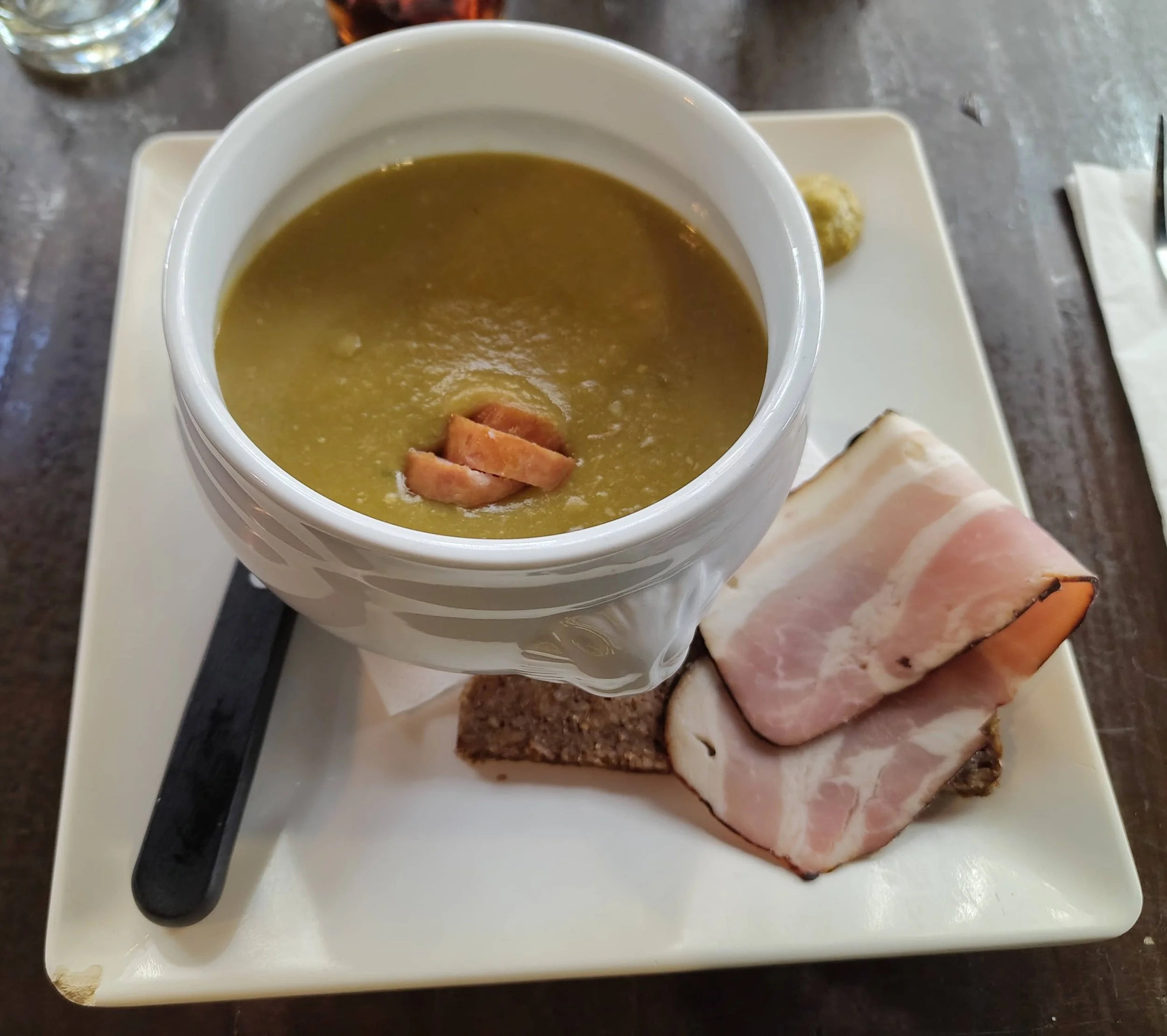 Erwtensoep – traditional Dutch pea soup with smoked sausage, served with rye bread, sliced pork, and mustard