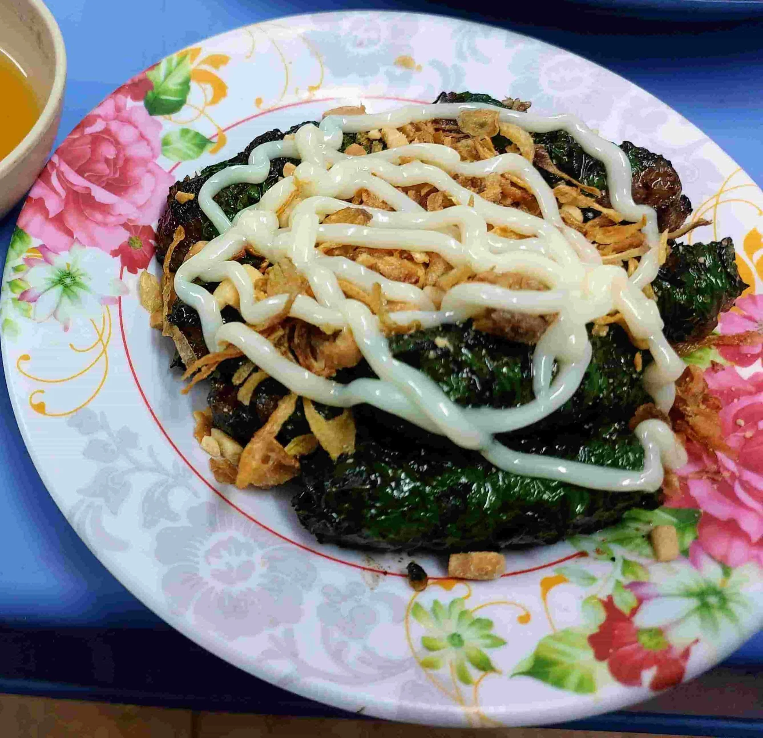 Grilled Bò Lá Lốt with beef wrapped in la lot leaves, garnished with crispy shallots and mayo
