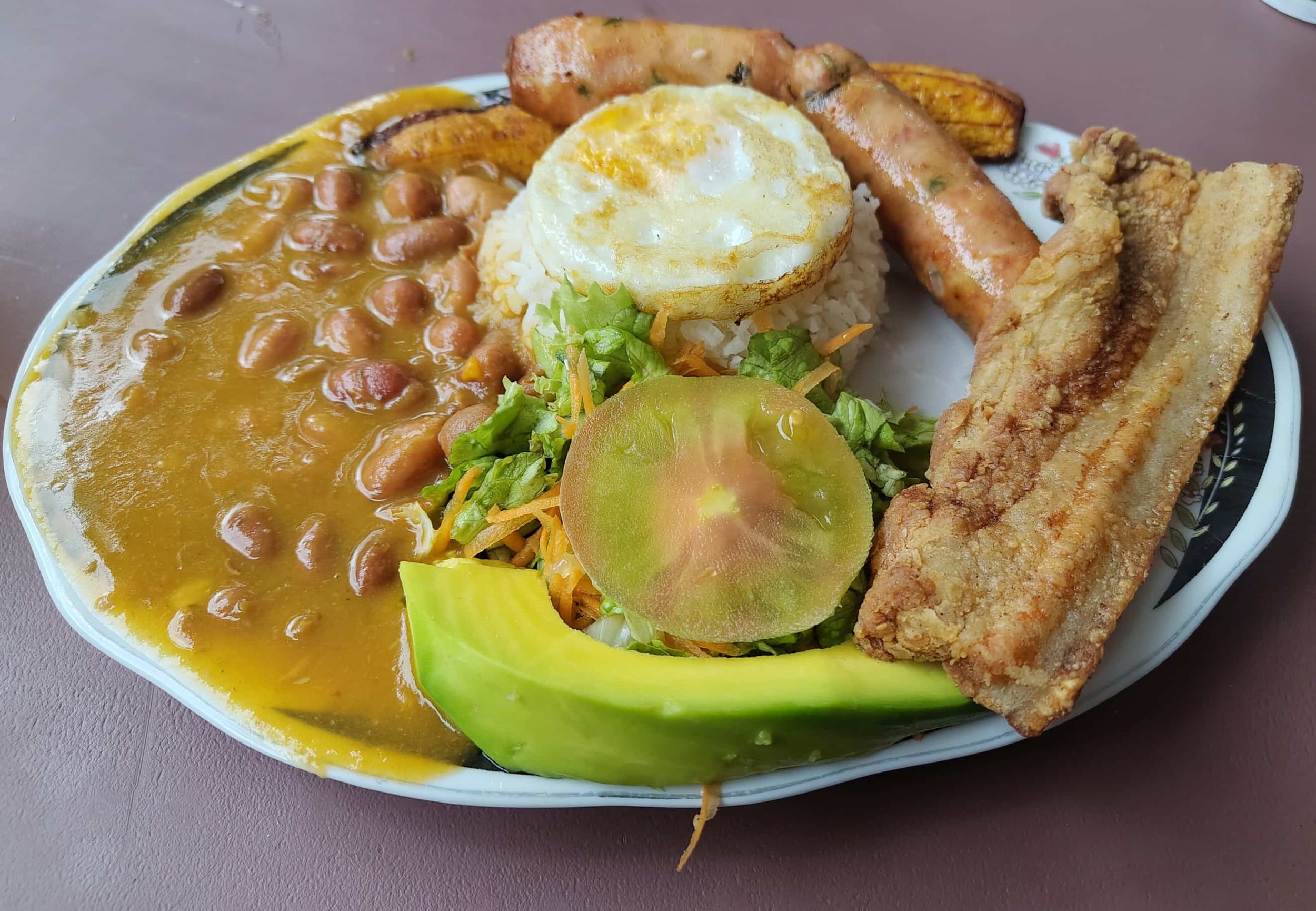 Bandeja paisa – Colombian platter with beans, rice, tomato, avocado, egg, plantain, chorizo, and chicharrón