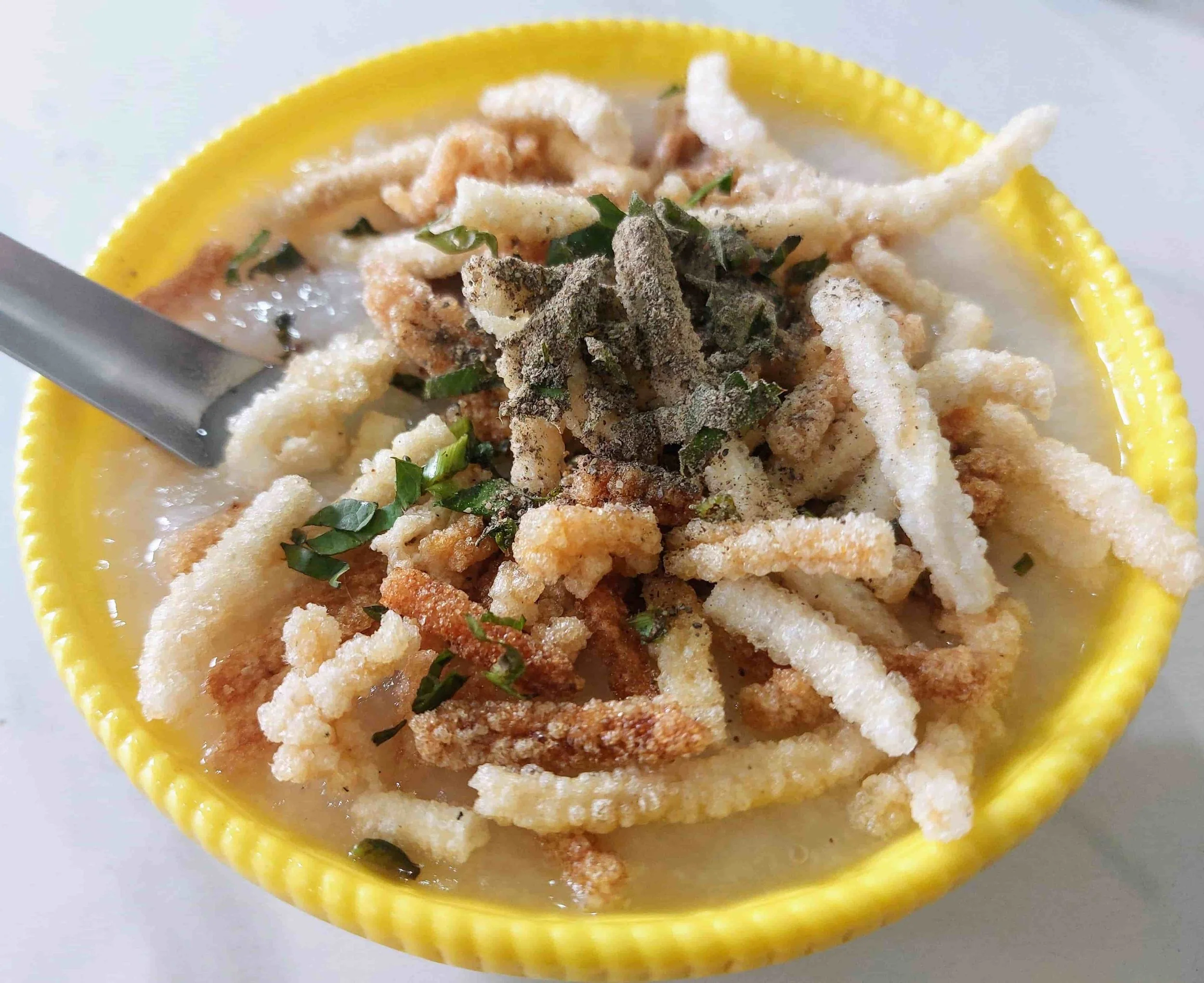 Sanpiau – traditional Mizo rice porridge from Mizoram topped with herbs, and crispy rice crackers