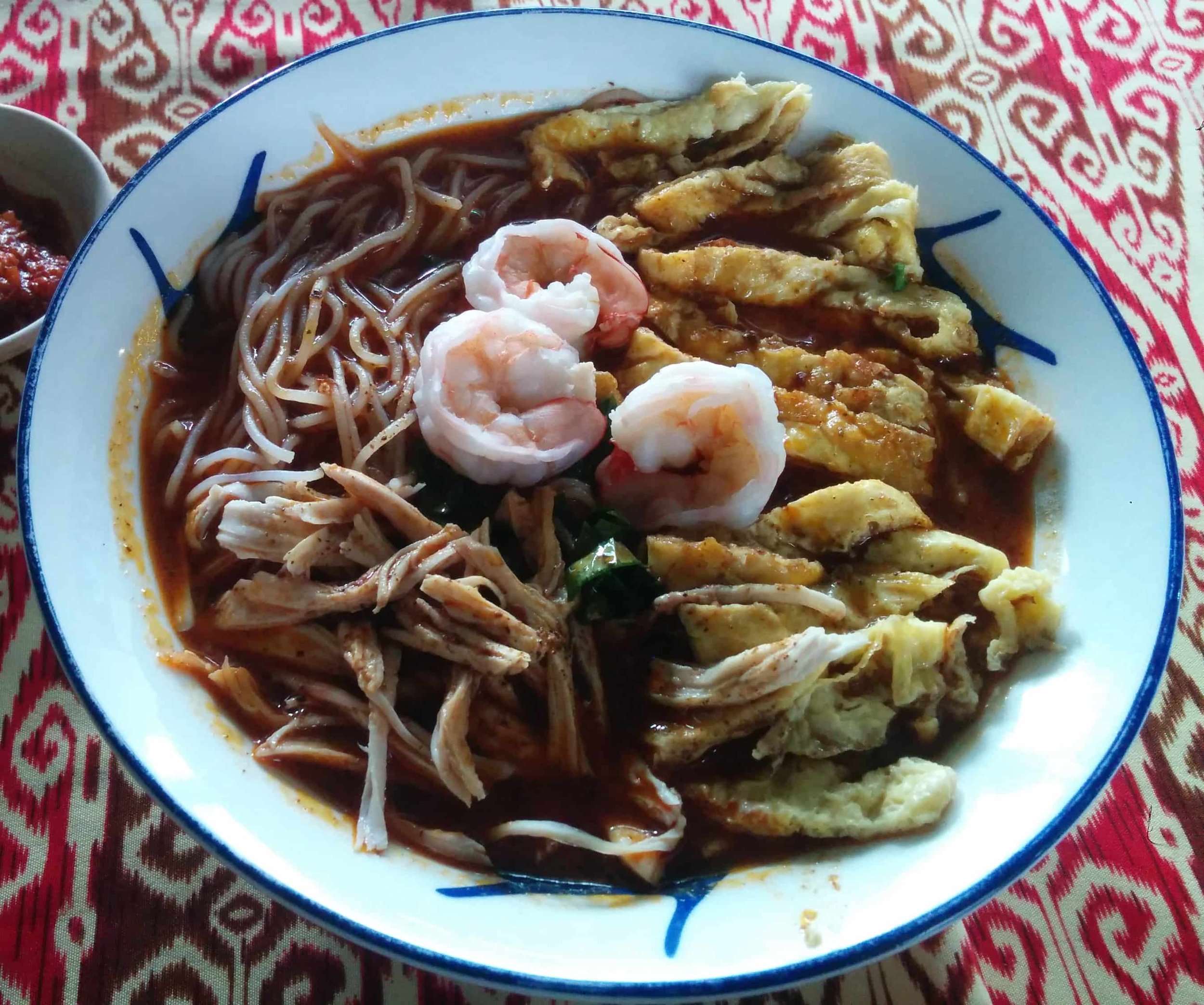 Sarawak Laksa from Malaysian Borneo with rice vermicelli, prawns, chicken, omelette strips and spicy coconut broth