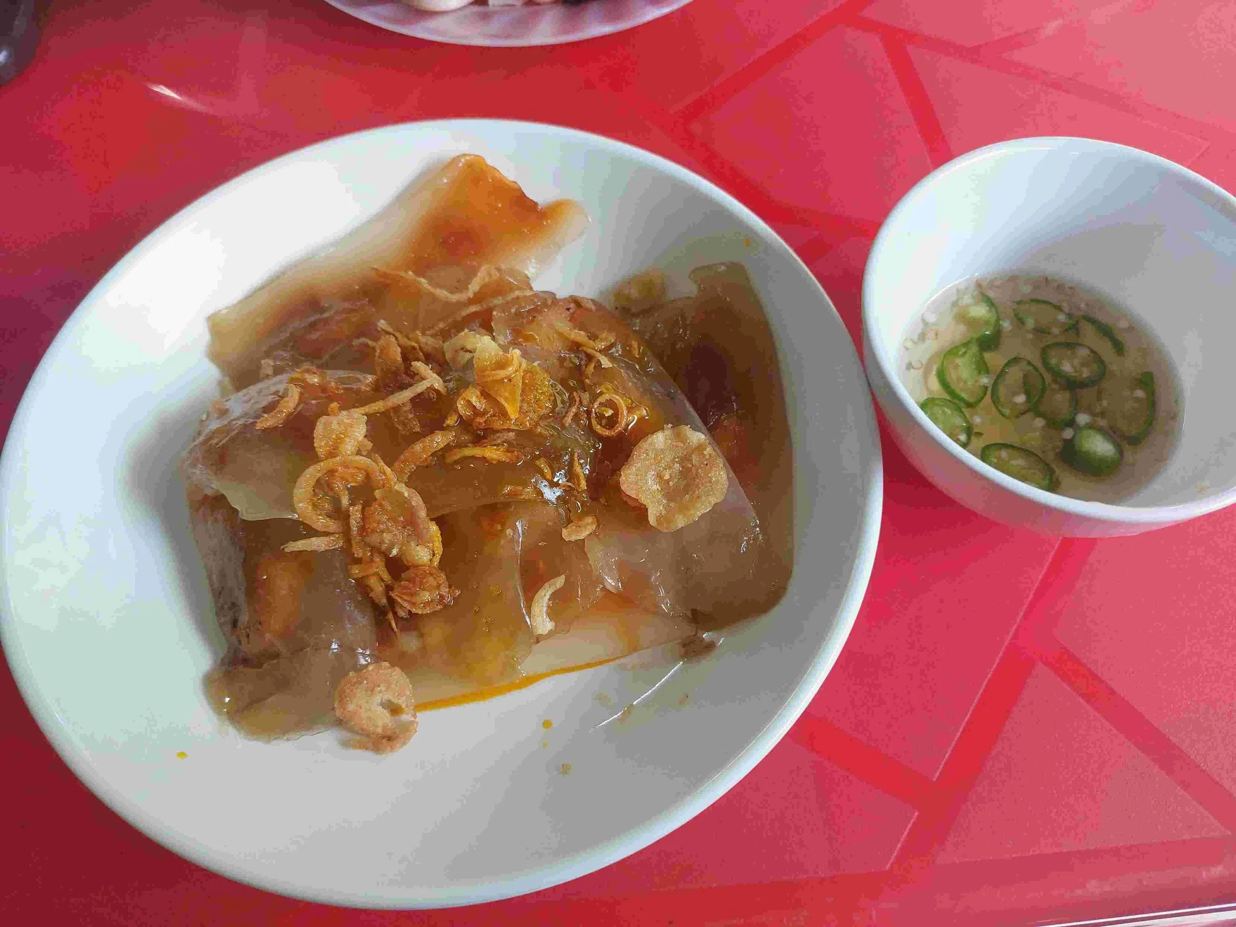 Bánh Bột Lọc – Vietnamese translucent tapioca dumplings filled with shrimp and pork, topped with crispy shallots, served with a bowl of nước chấm dipping sauce