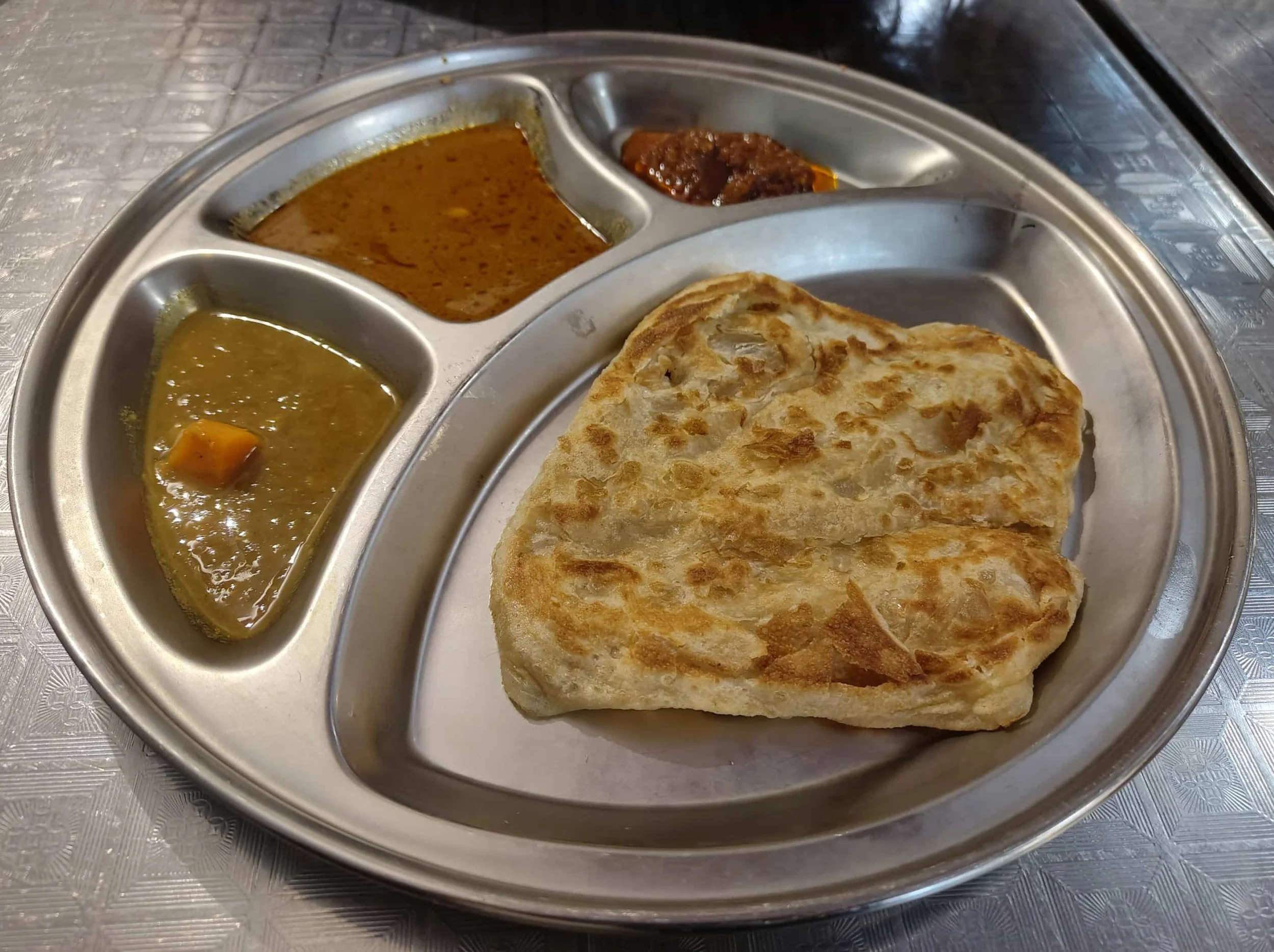 Traditional Malaysian roti canai served with dhal, meat curry and sambal