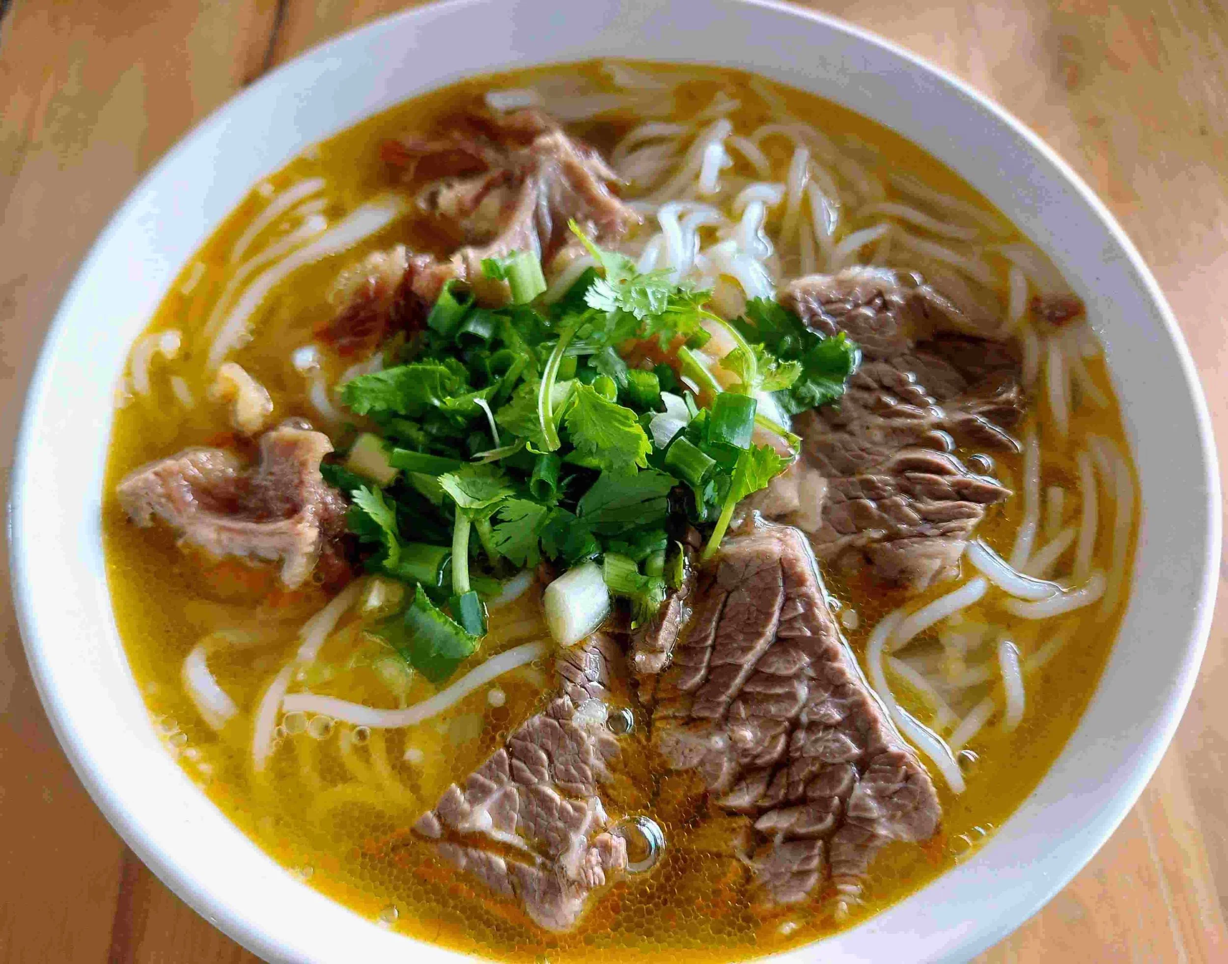 Bún Bò Huế – spicy Vietnamese beef noodle soup with lemongrass broth, beef slices, and fresh herbs