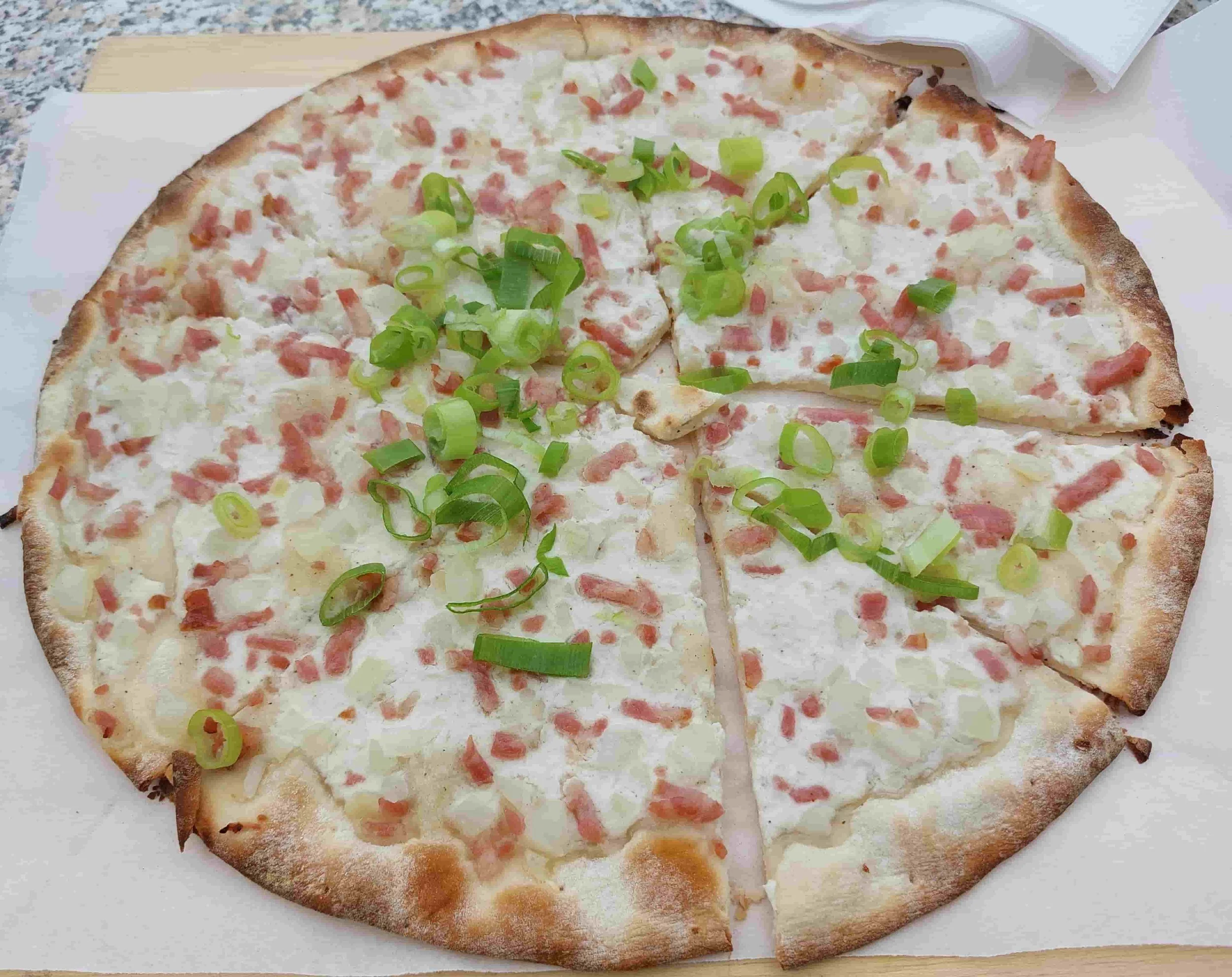 German Flammkuchen thin crispy flatbread with cream, onions, and bacon