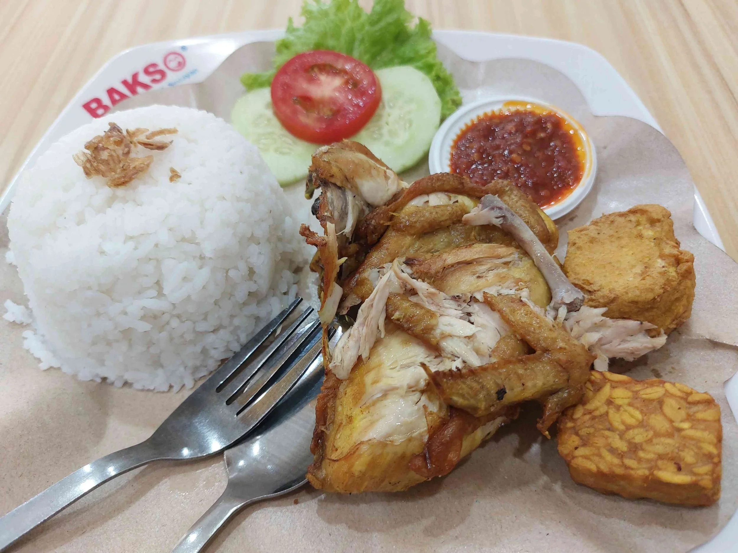 Ayam Penyet Indonesian smashed fried chicken served with tempeh, steamed rice, spicy sambal, lettuce, tomato, and cucumber