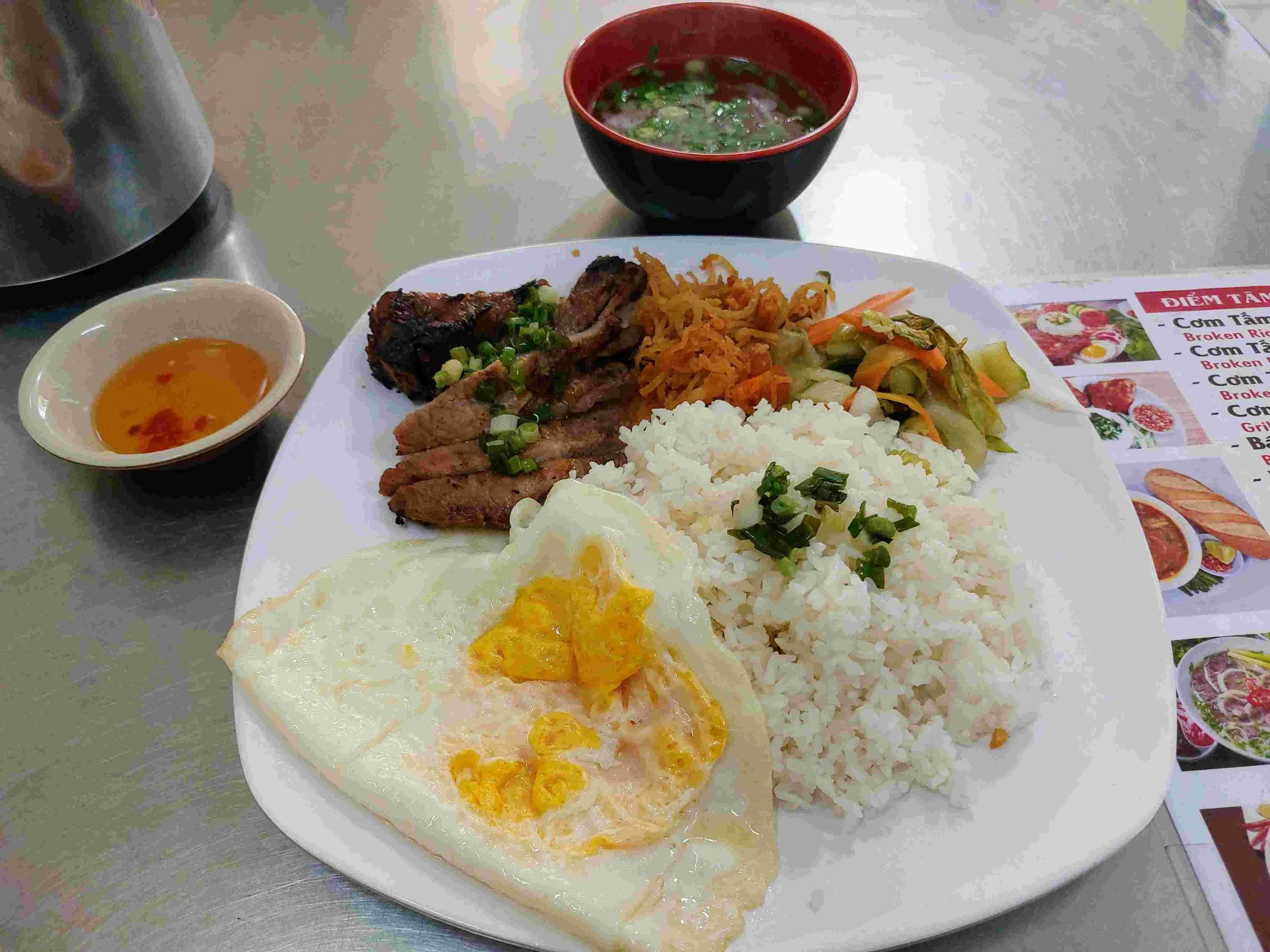 Cơm tấm with grilled pork, fried egg, shredded pork skin, and pickled vegetables on broken rice