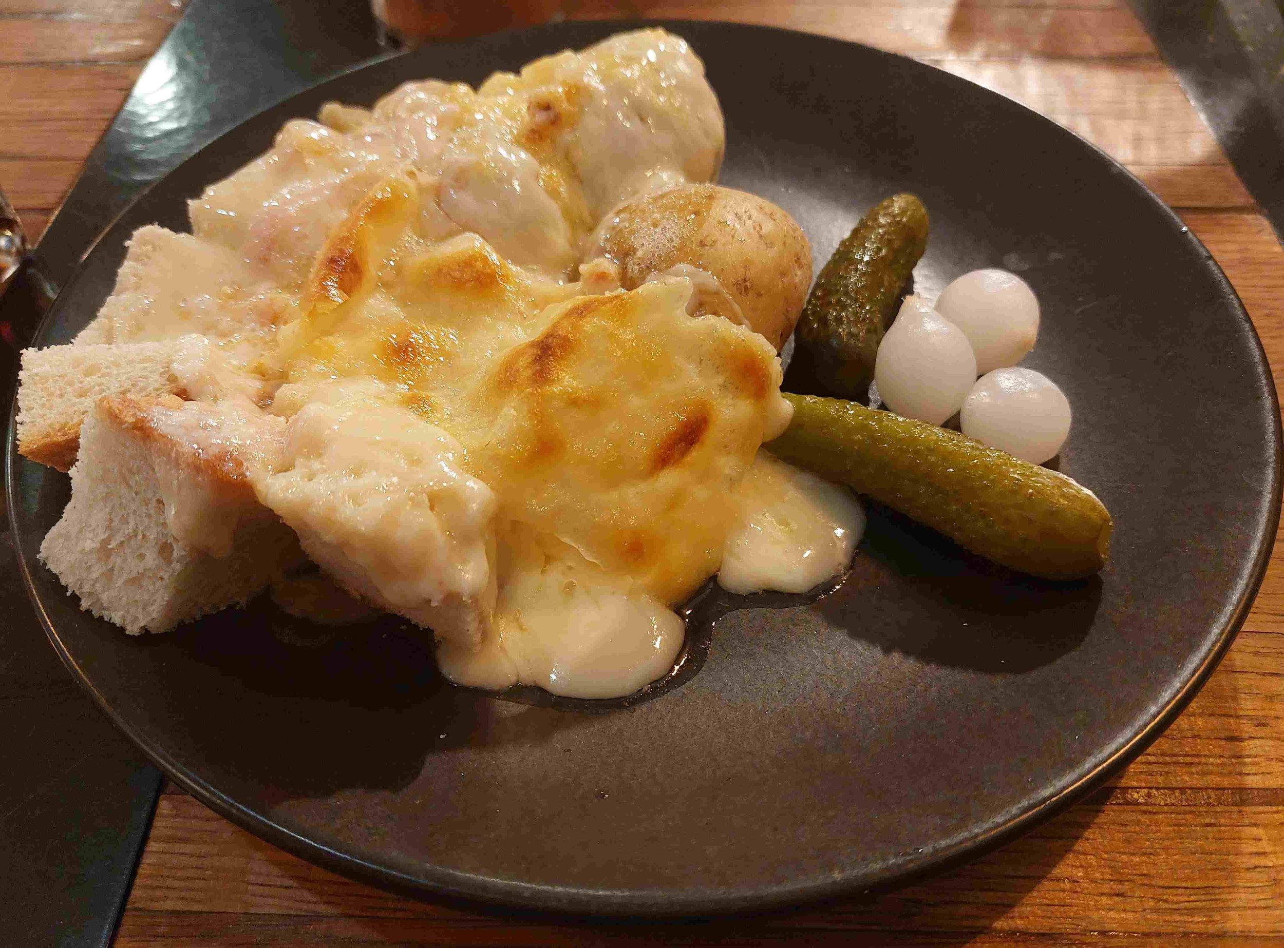 Raclette – melted cheese served with potatoes, onion, bread, and pickles