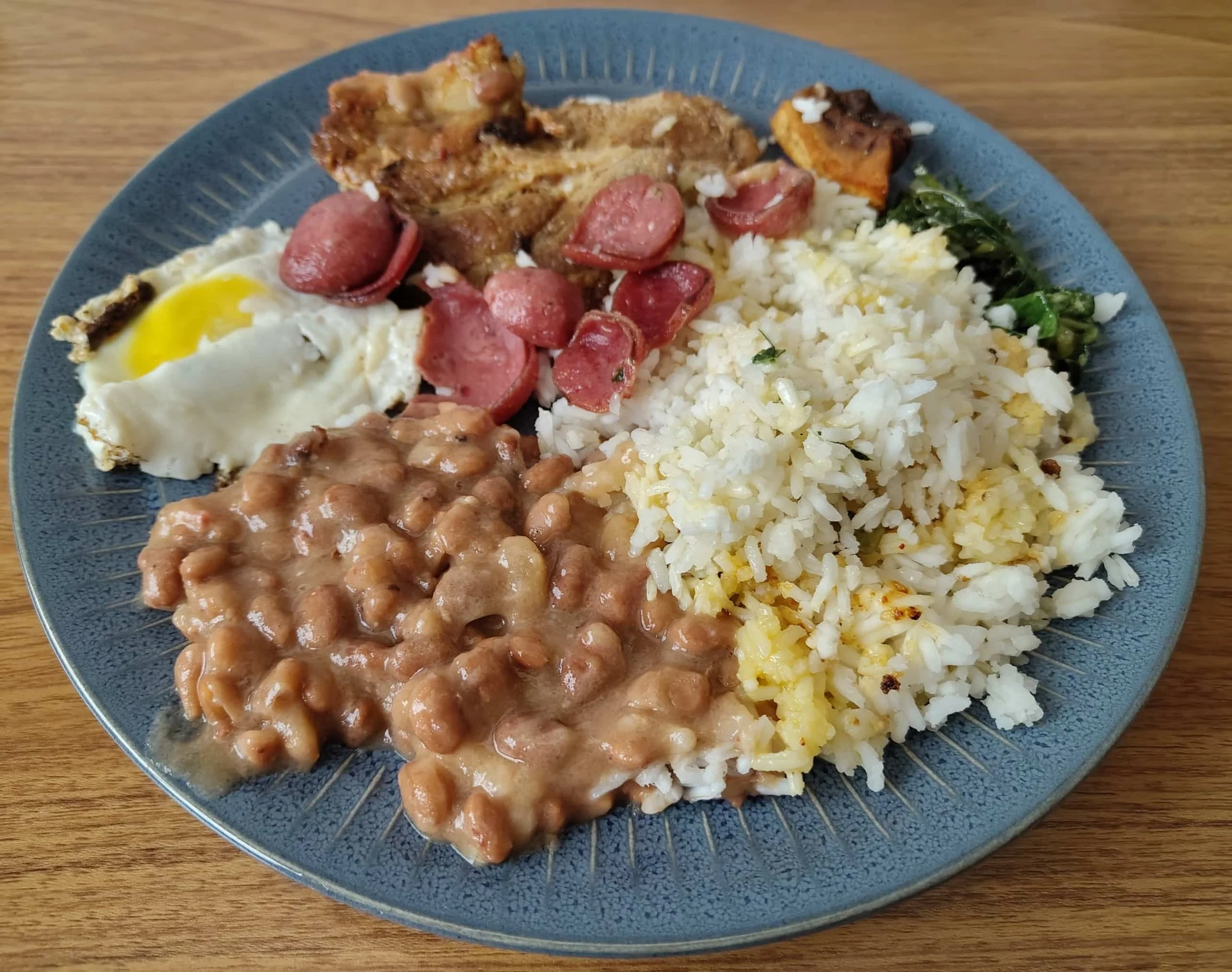 Traditional Brazilian virado à paulista with beans, rice, pork, fried egg and collard greens
