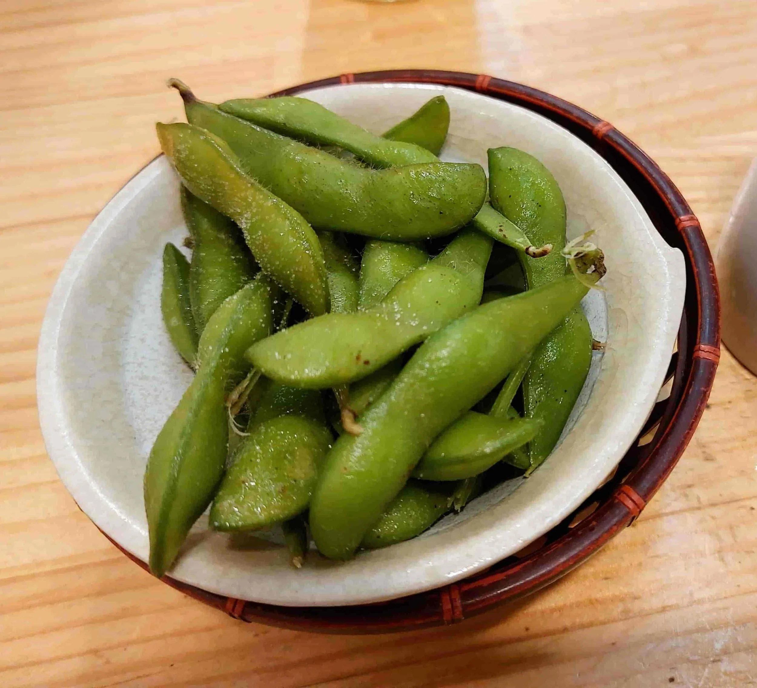 Steamed edamame pods sprinkled with sea salt served in a bowl
