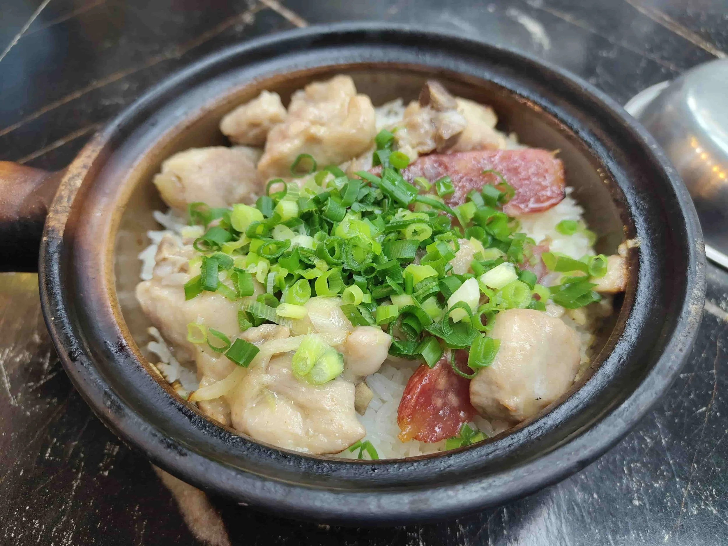 Hong Kong claypot rice topped with chicken, Chinese sausage, and scallions