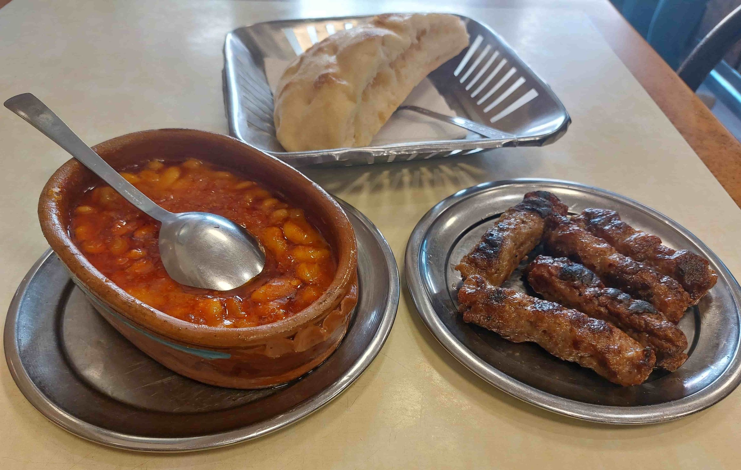 North Macedonian kebapi grilled minced meat sausages served with tavče gravče traditional baked beans and flatbread