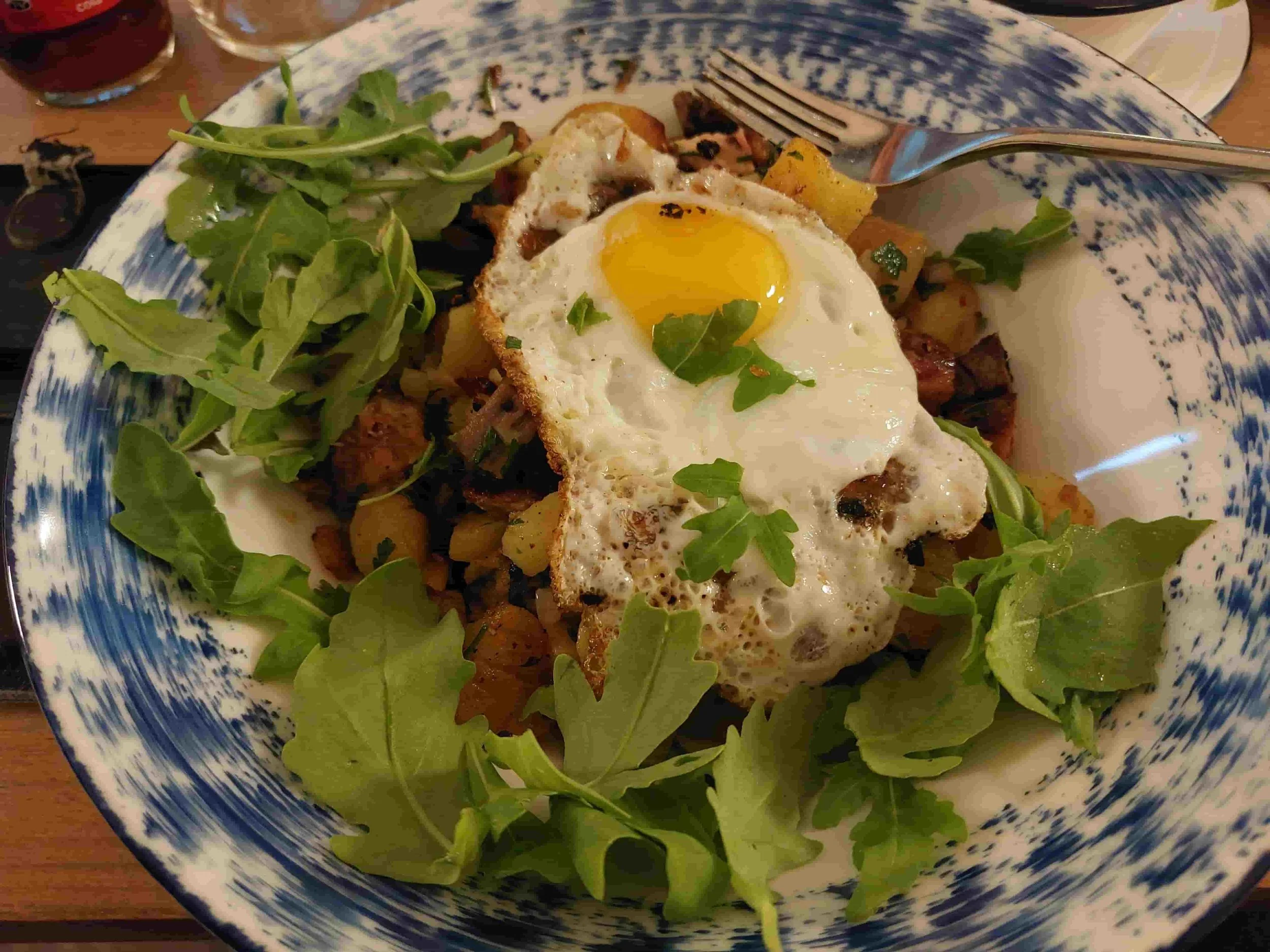 Austrian Tiroler Gröstl pan-fried potatoes with meat, onion, salad and fried egg