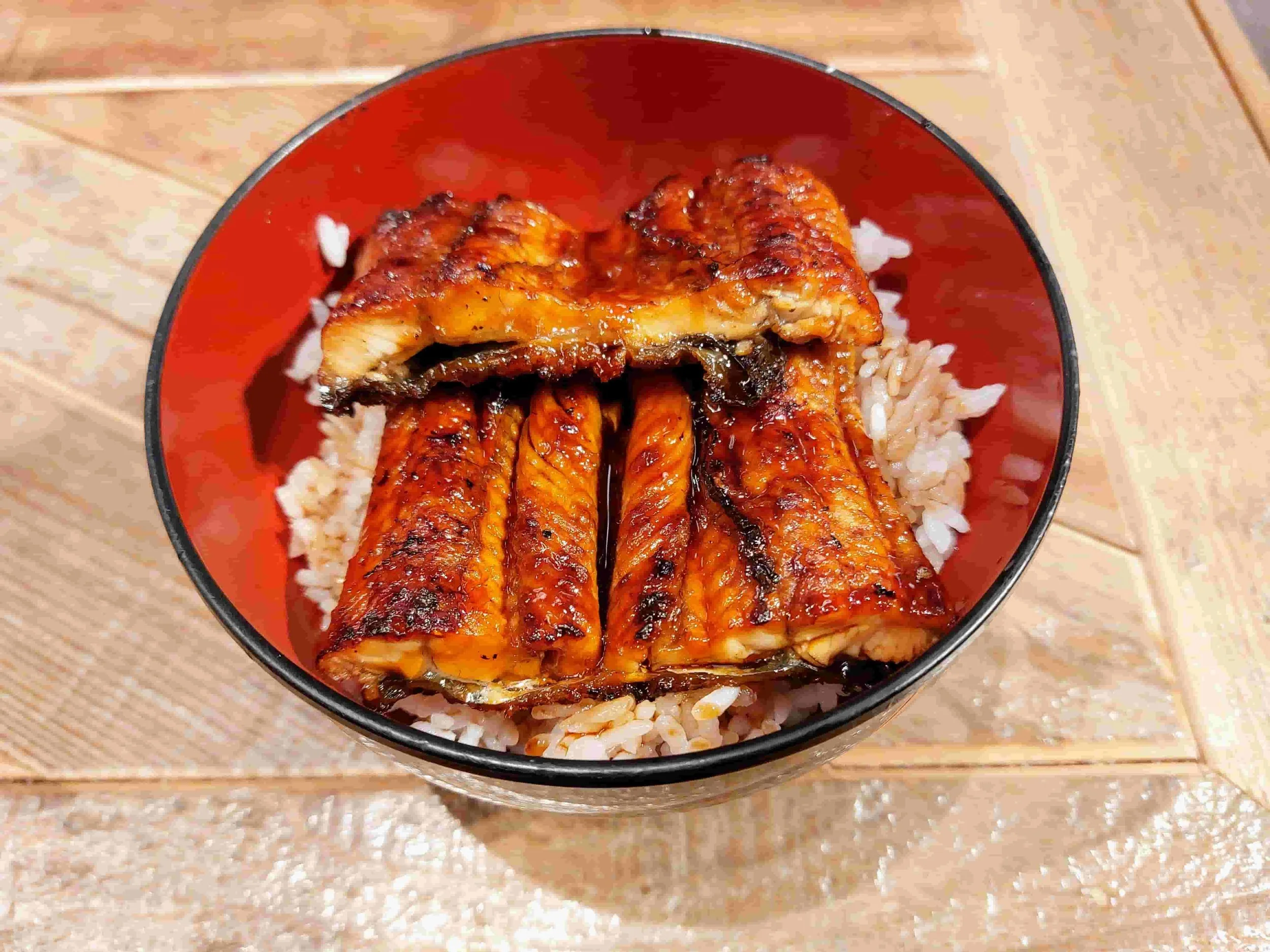 Grilled eel glazed with sweet soy sauce served over steamed rice in a traditional unadon bowl