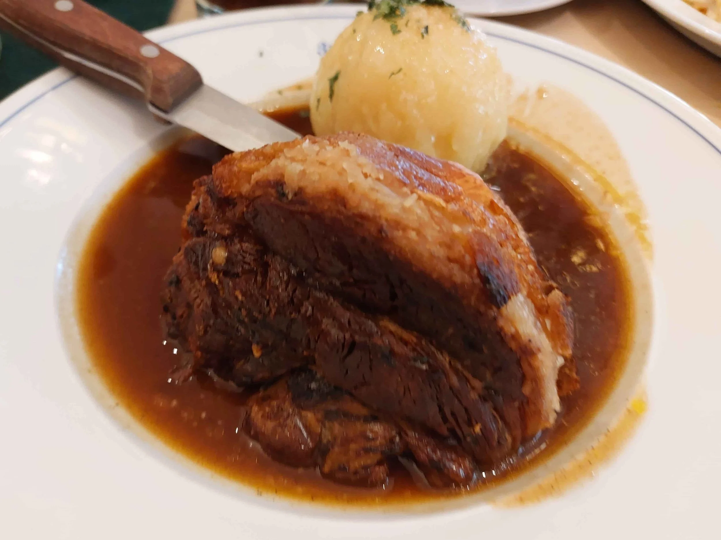 German Schweinshaxe roasted pork knuckle with Kartoffelknödel potato dumplings and gravy