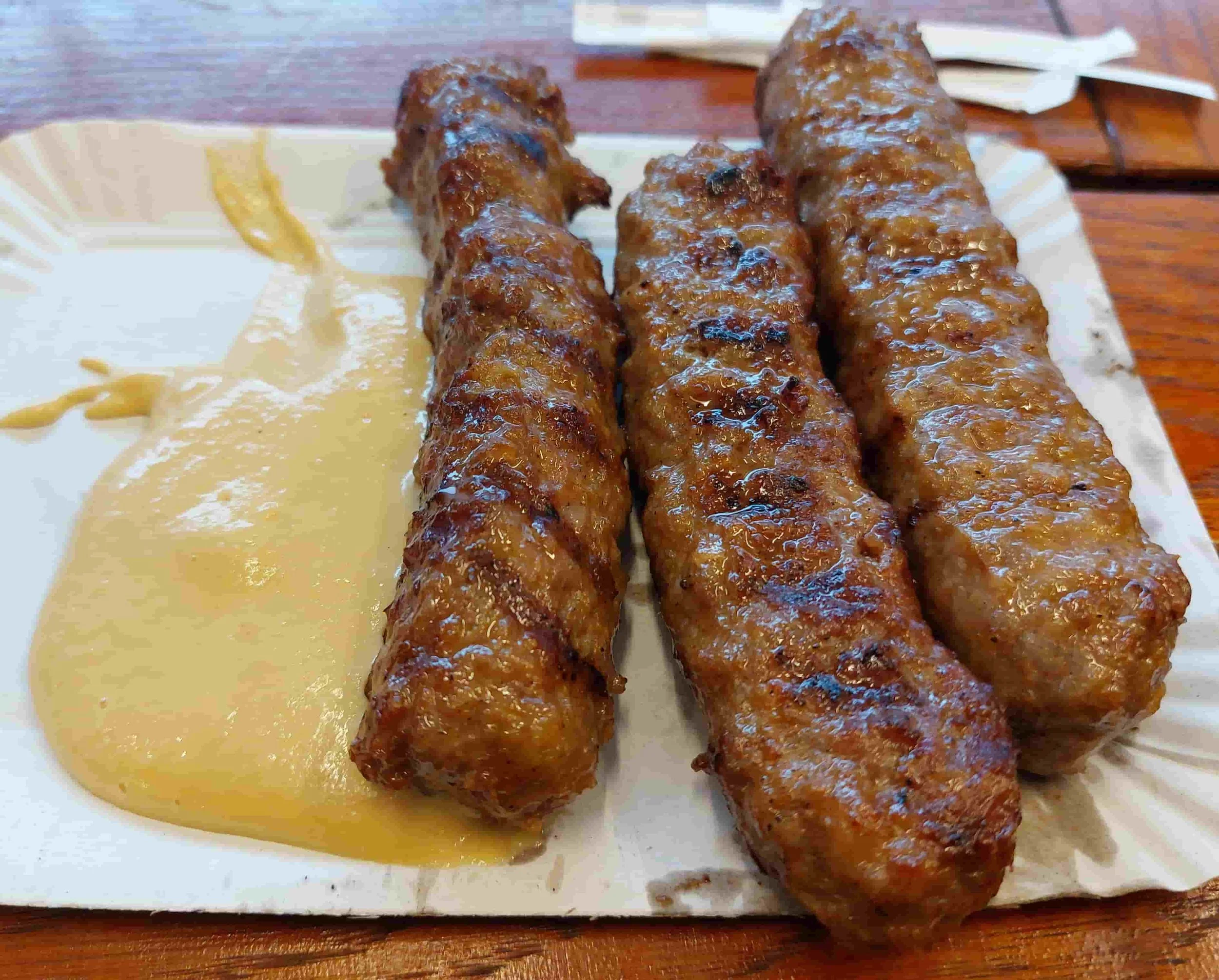 Three Romanian mici grilled sausages served with mustard