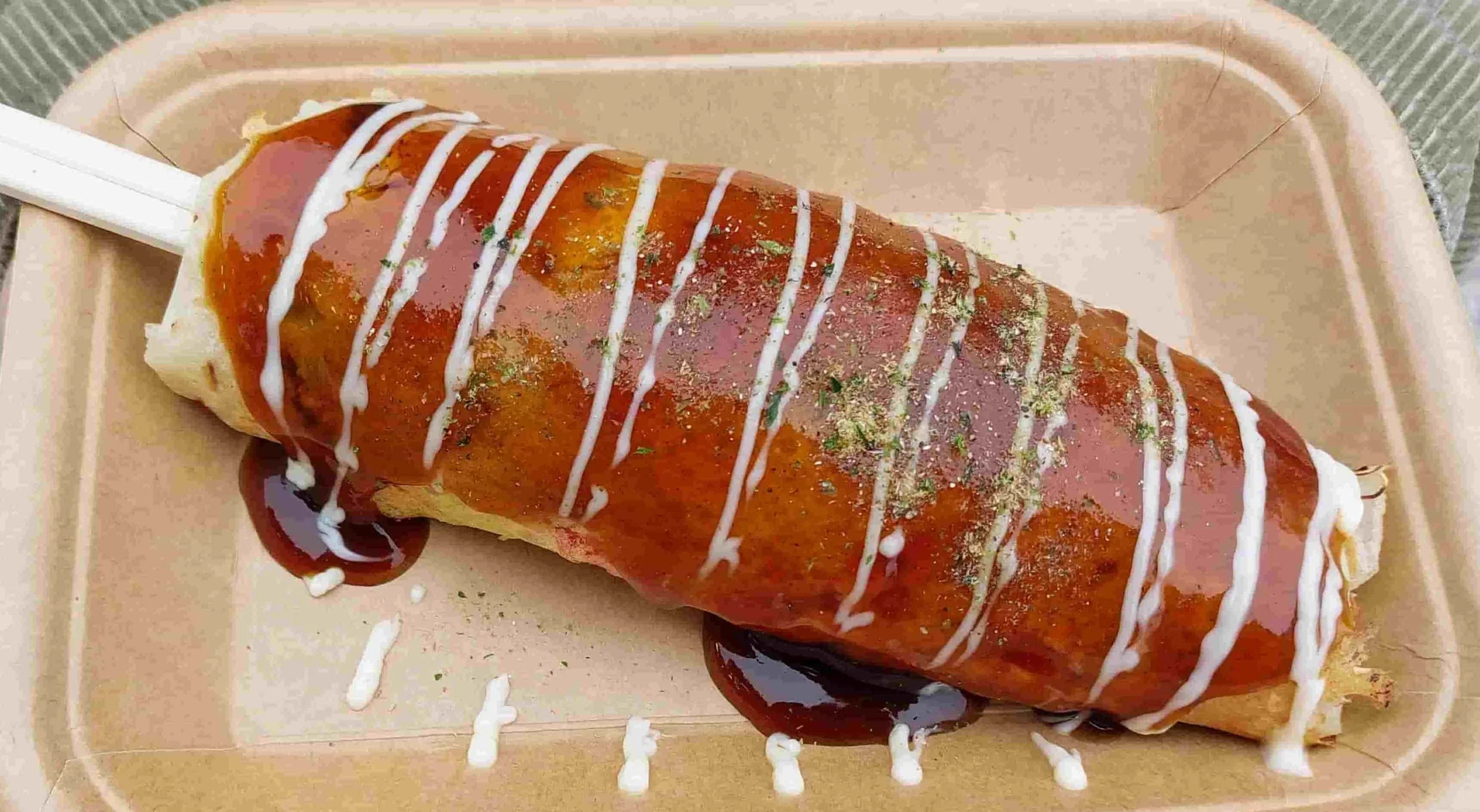 Hashimaki – a savoury Japanese pancake wrapped around chopsticks, topped with sauce, mayo, seaweed, and bonito flakes.