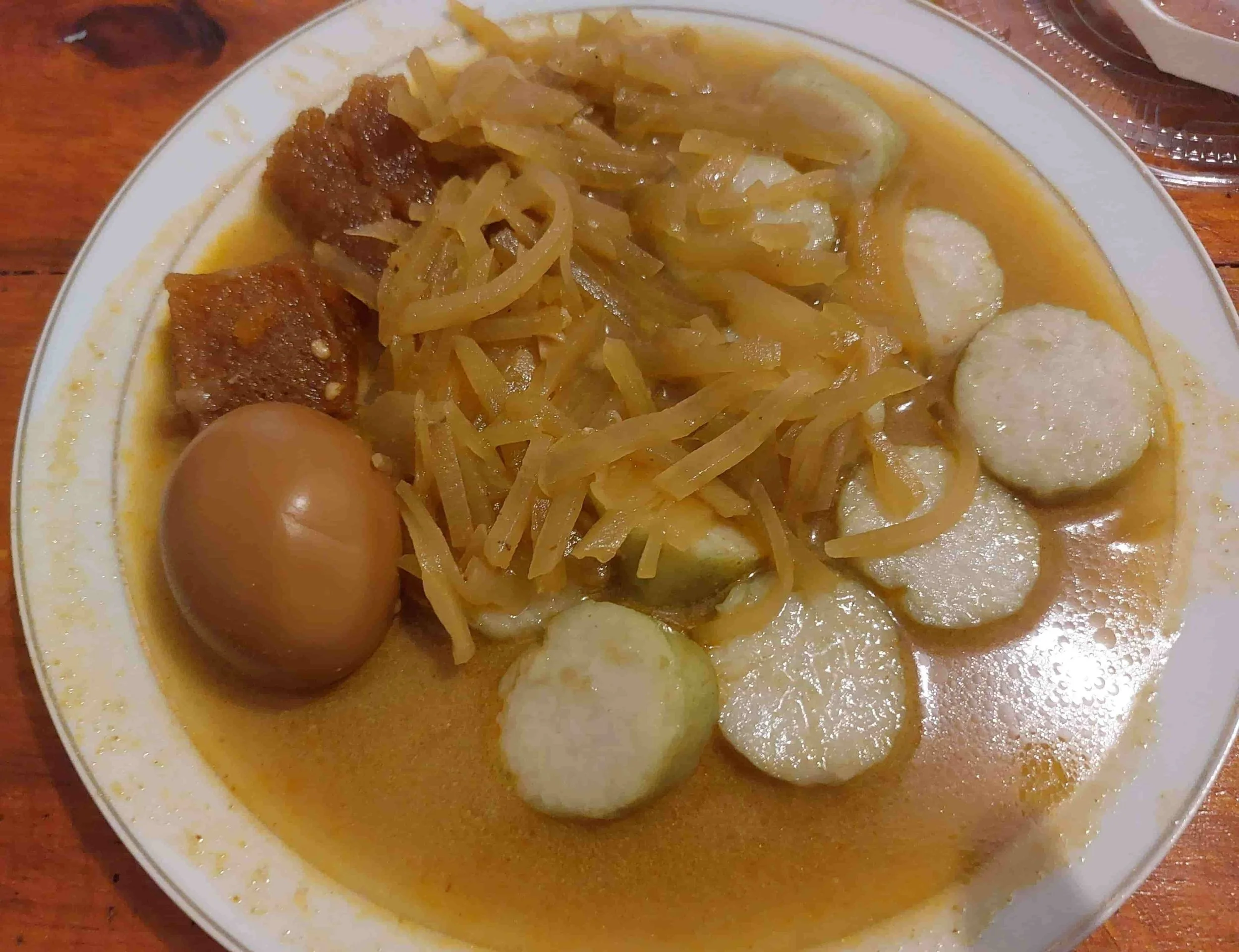 Indonesian Lontong Sayur with chayote, boiled egg, rice cakes, and spicy orange krecek in coconut curry soup