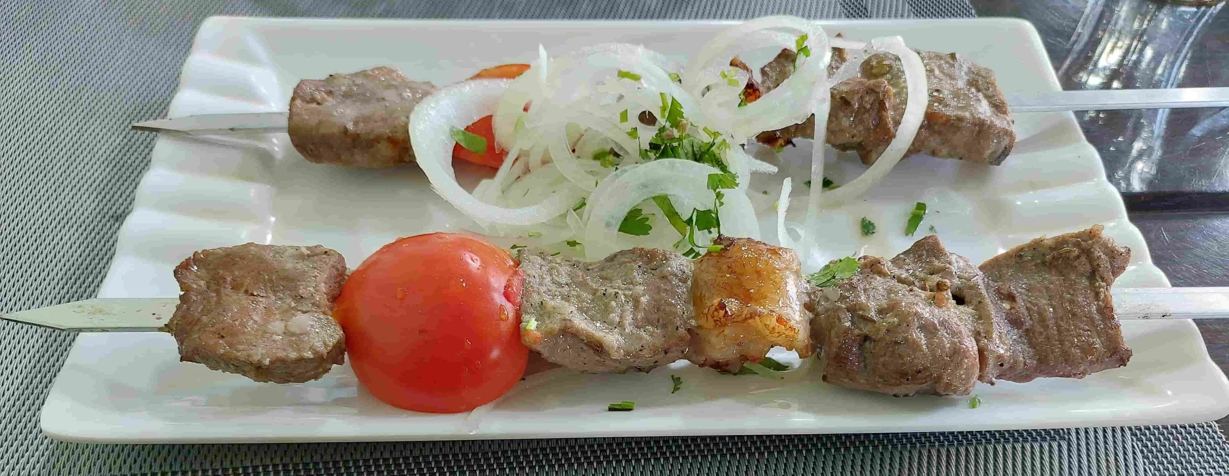 Uzbek Shashlik skewered grilled meat with tomatoes and onions