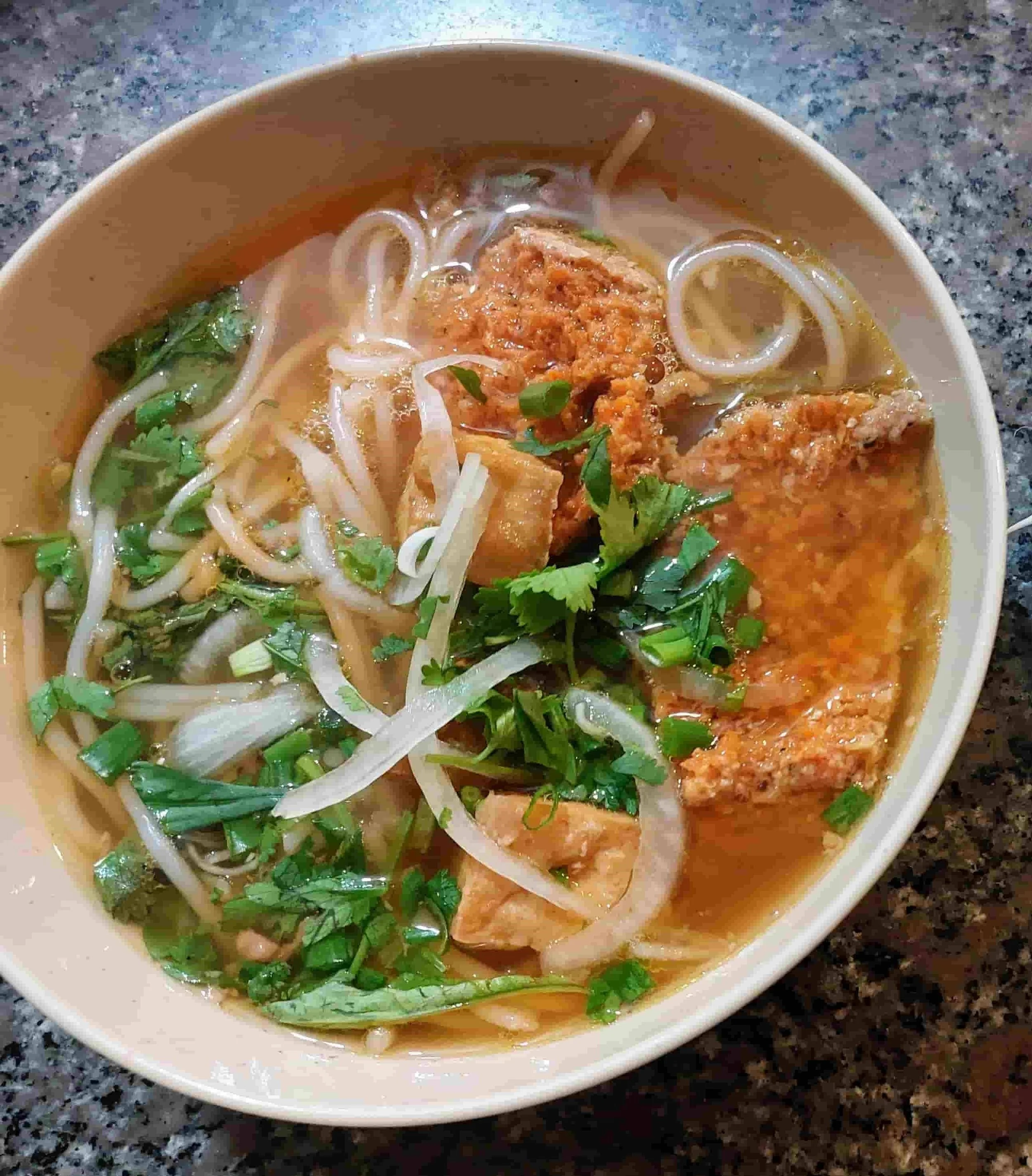 Vietnamese Bún Riêu noodle soup with crab meat, rice noodles, tofu, and aromatic herbs