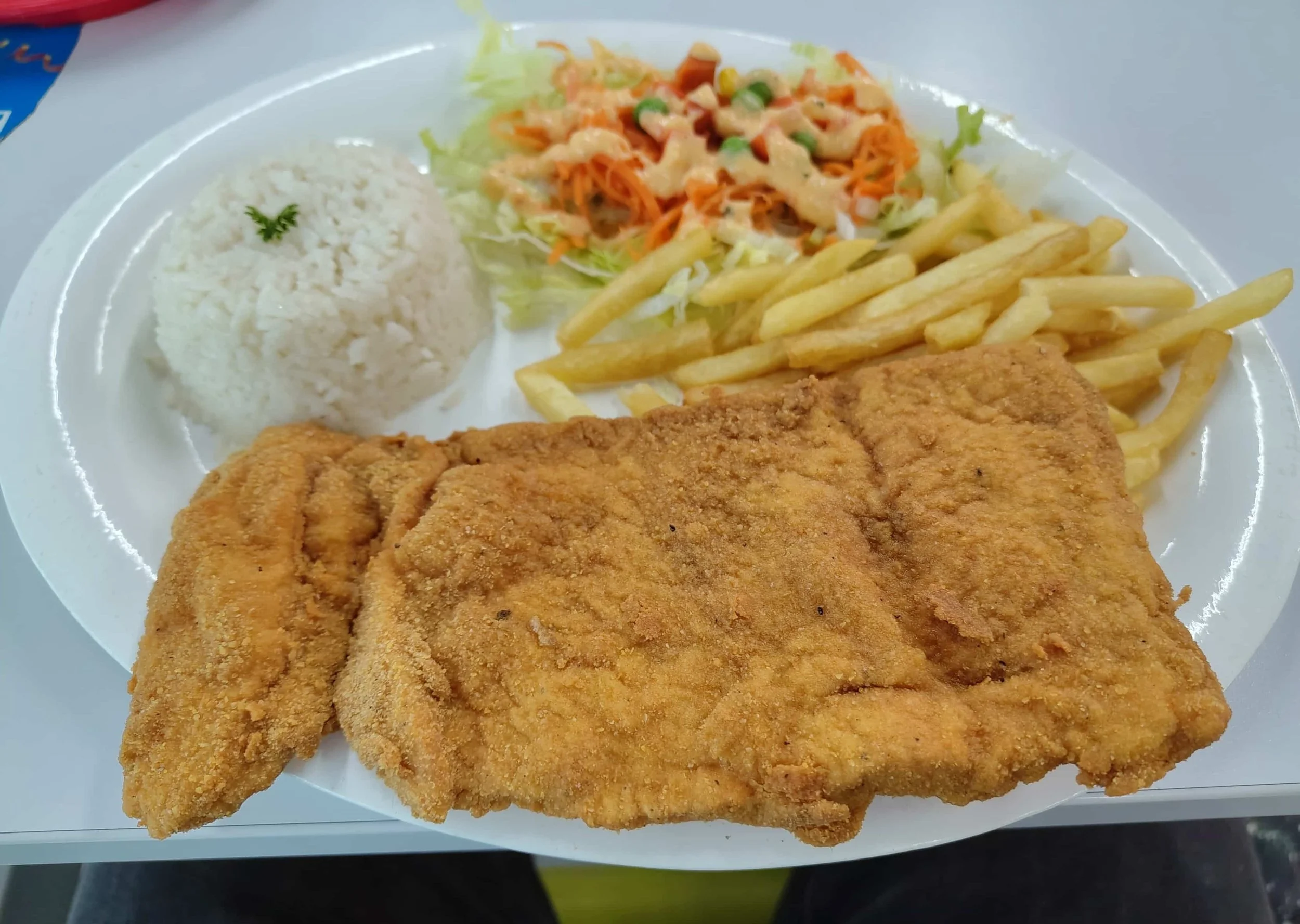 Chuleta valluna – Colombian breaded pork cutlet served with fries, rice, and salad