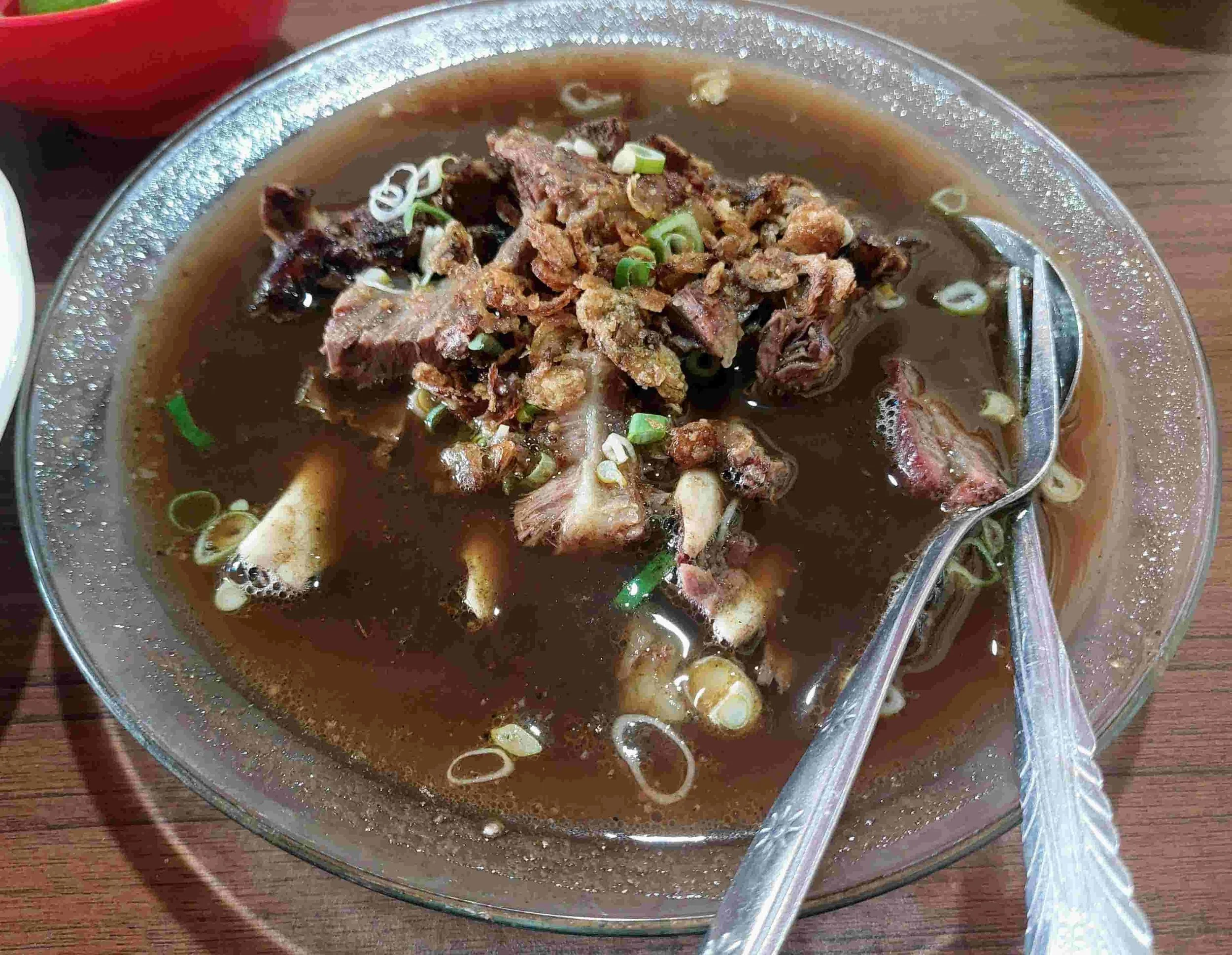 Makassar beef rib soup in a dark, spiced broth made with kluwak, coriander, and nutmeg