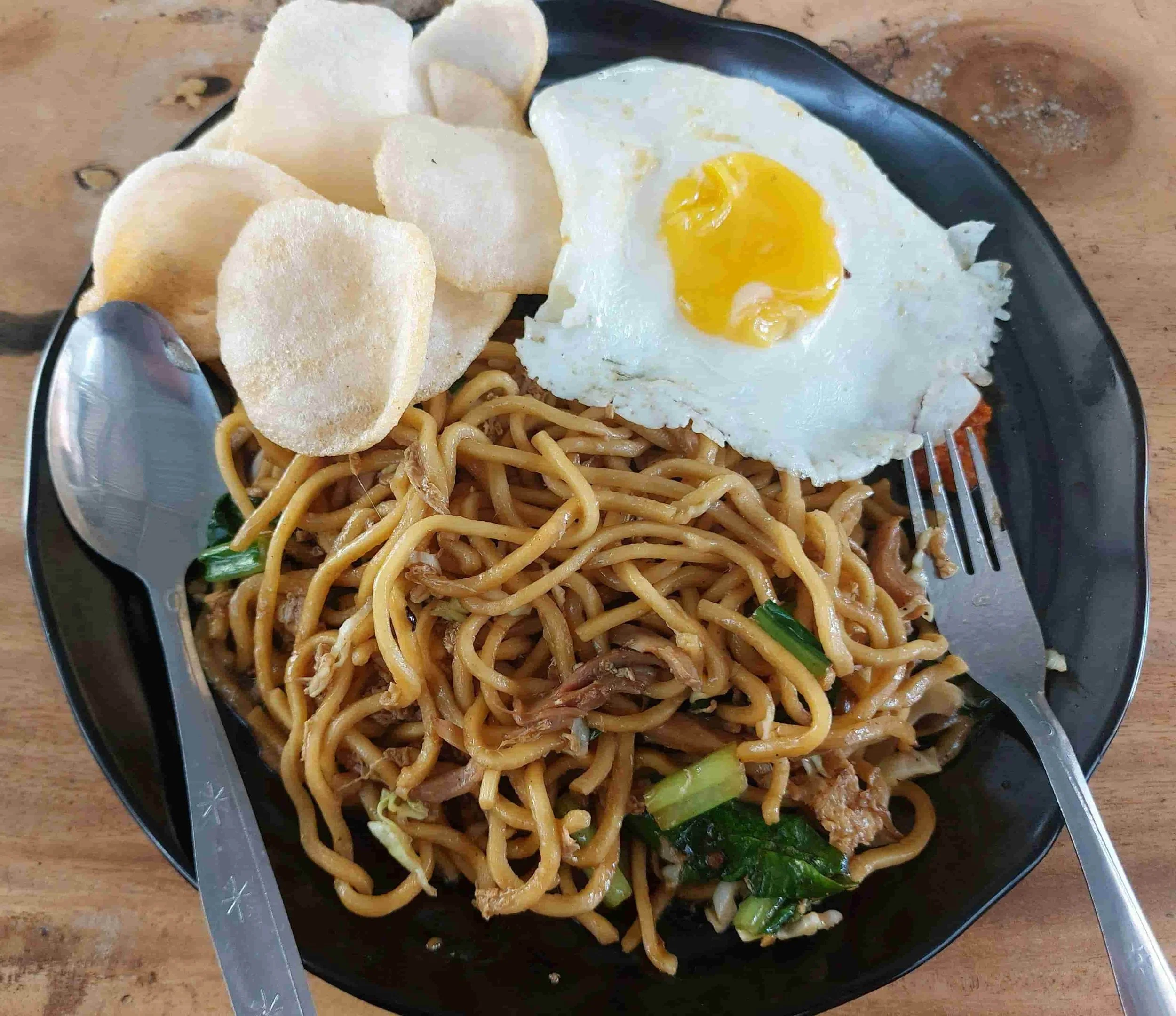Indonesian mie goreng fried noodles topped with fried egg and served with crispy crackers