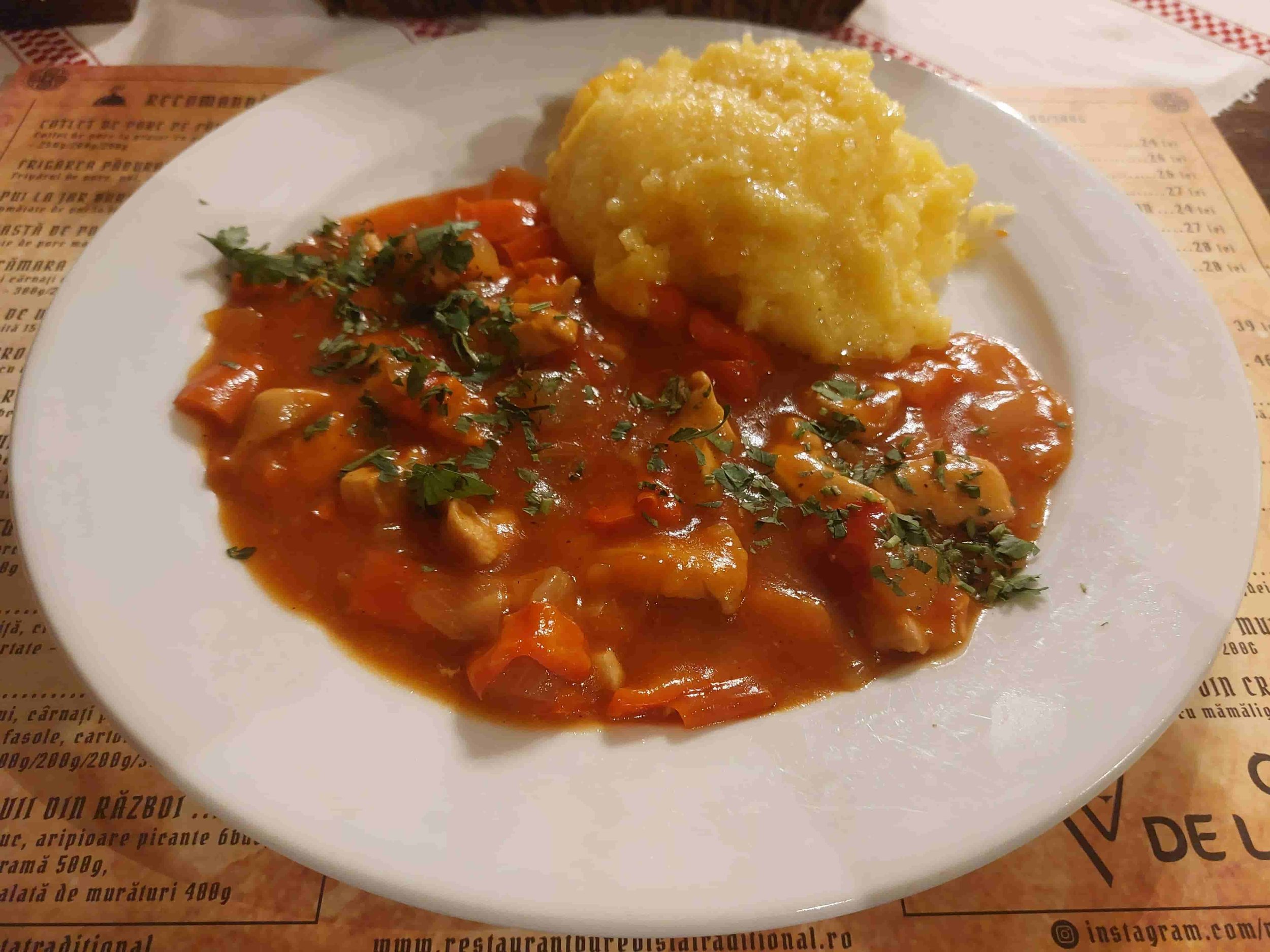 Ostropel de pui Romanian chicken stew in garlicky tomato sauce served with mămăligă