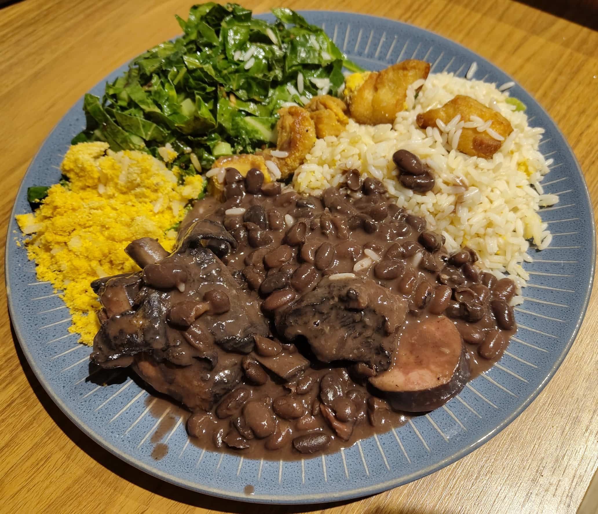 Traditional Brazilian feijoada, a black bean and pork stew served with rice and traditional accompaniments