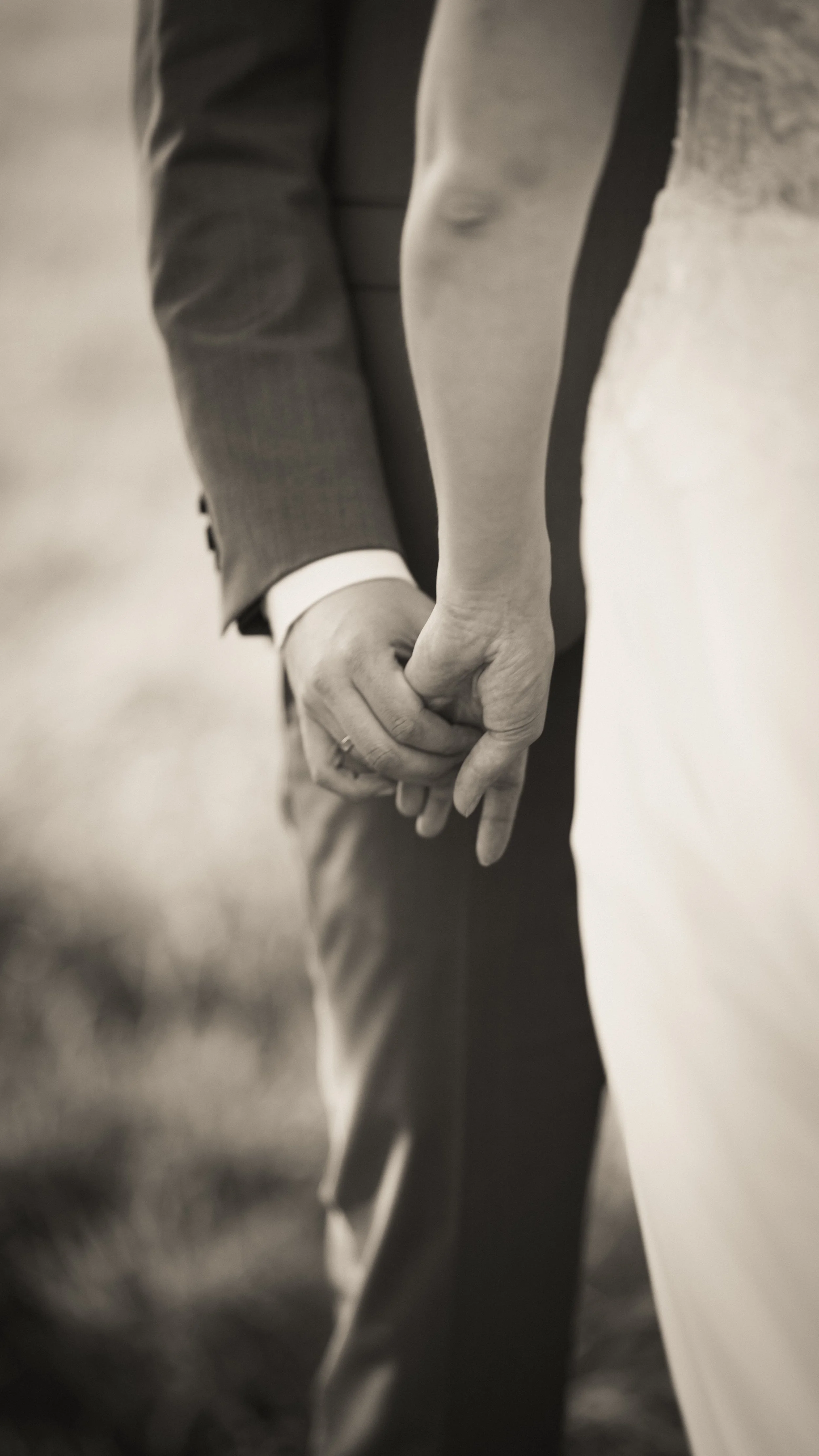 Nahaufnahme von zwei Personen, die sich an der Hand halten, bei einer formellen Veranstaltung, schwarz-weiß