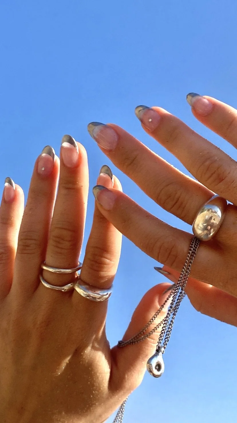 hand wearing the handmade sterling silver reflection ring against a blue sky