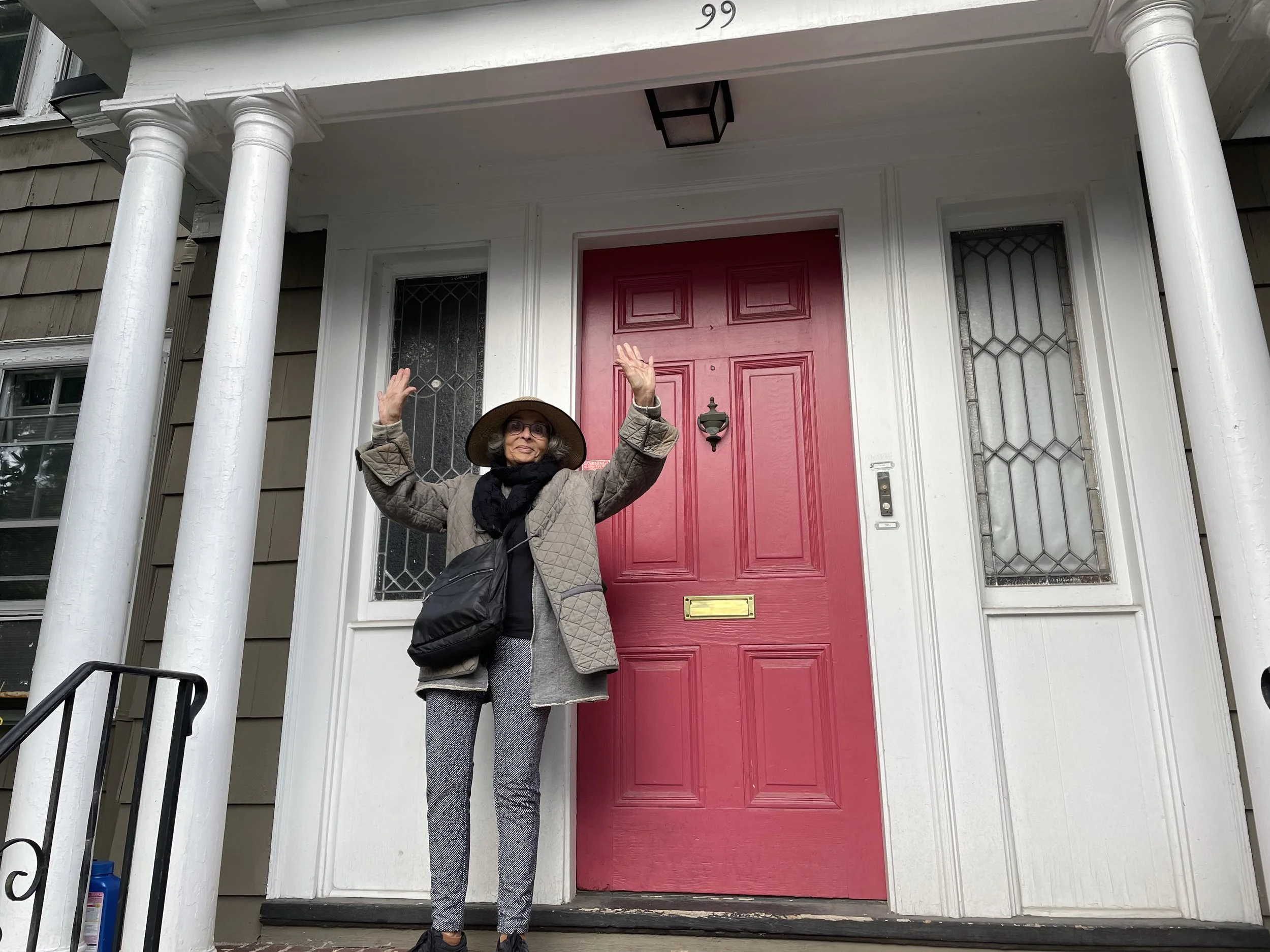 A woman standing in front of a building with a red door