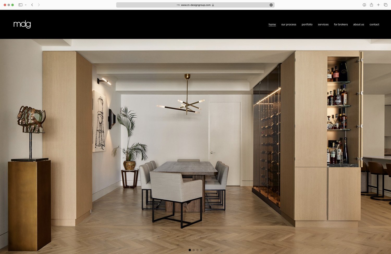 Modern dining room with wooden floors, a sculptural art piece on a pedestal, wall art, a dining table with upholstered chairs, a contemporary light fixture, and built-in wine storage with bottles.
