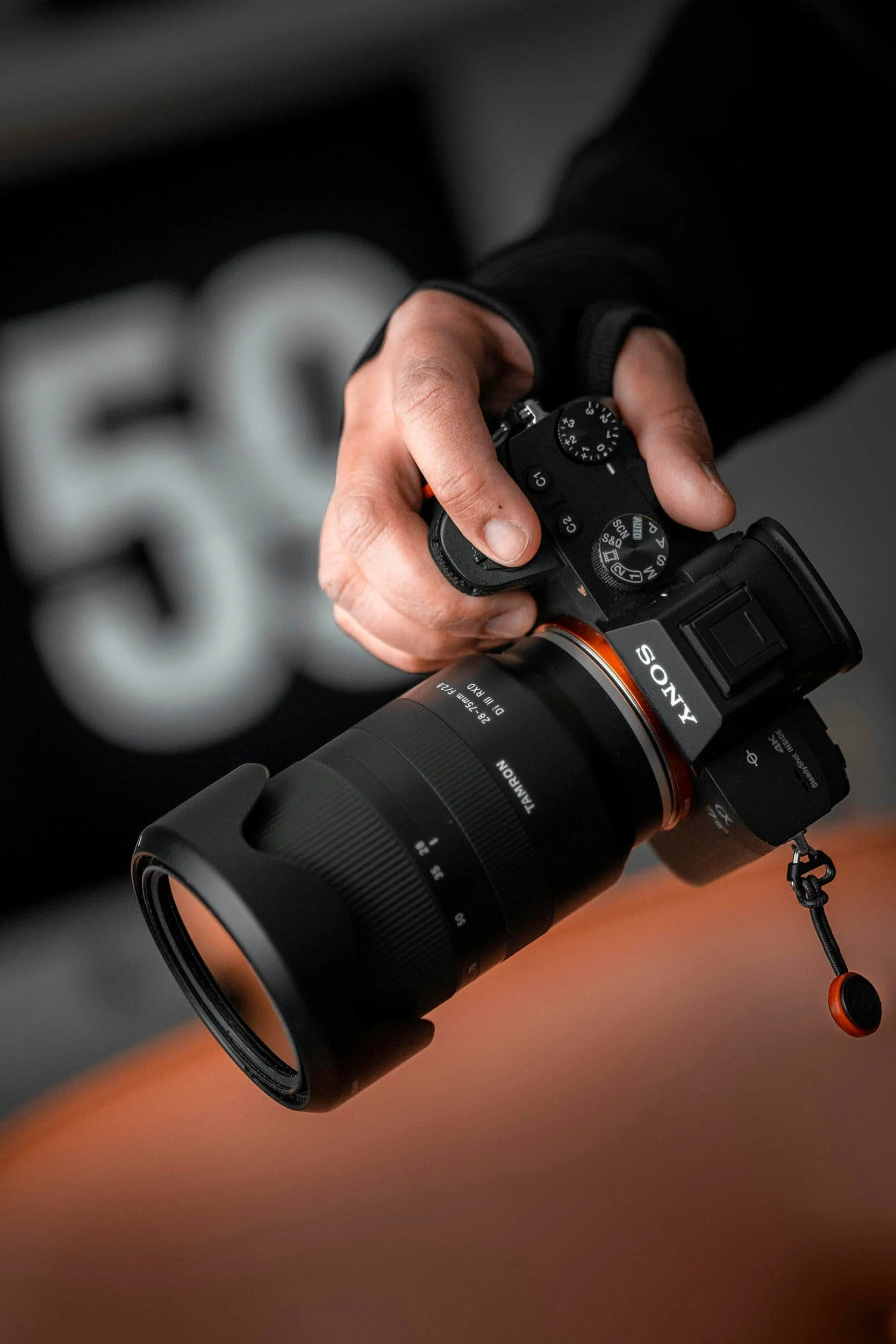 A person holding a Sony camera with a large zoom lens.