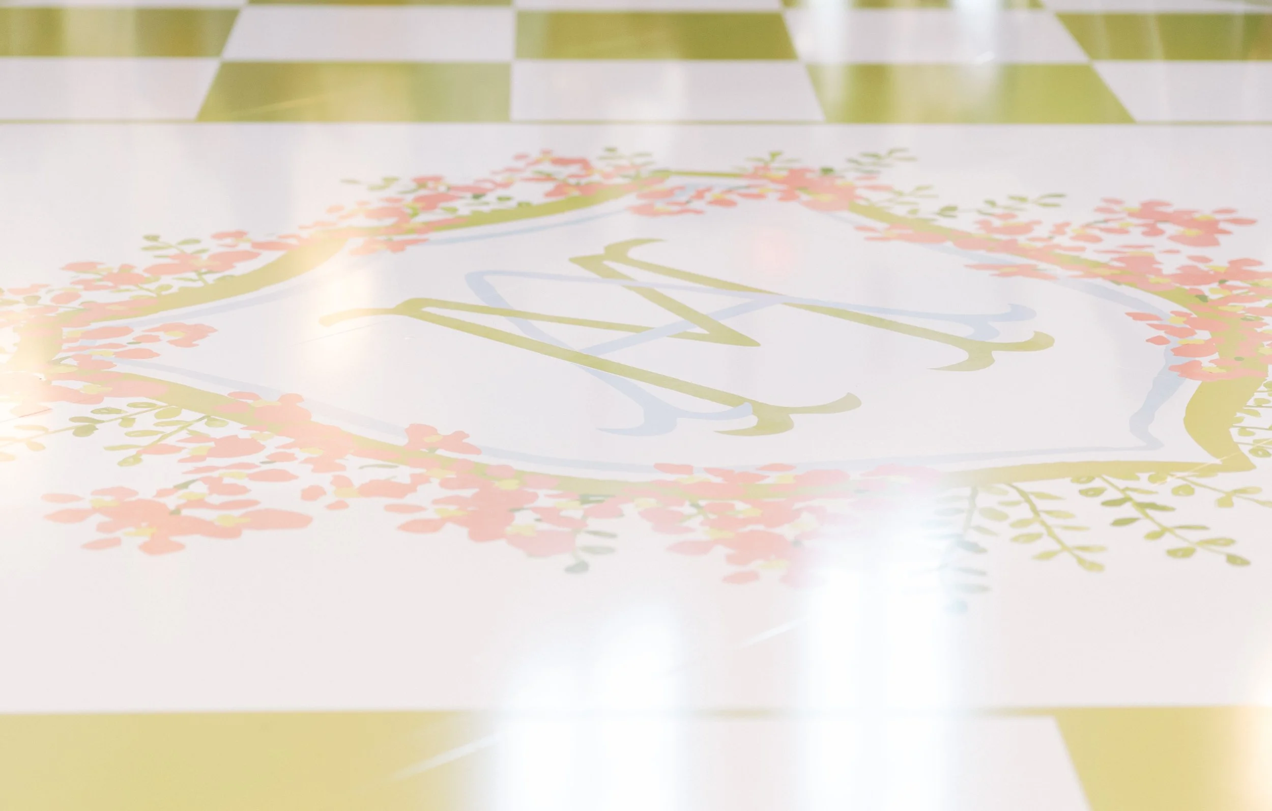 Close-up of a decorative table with a monogrammed initial 'M' surrounded by pink and green floral design.