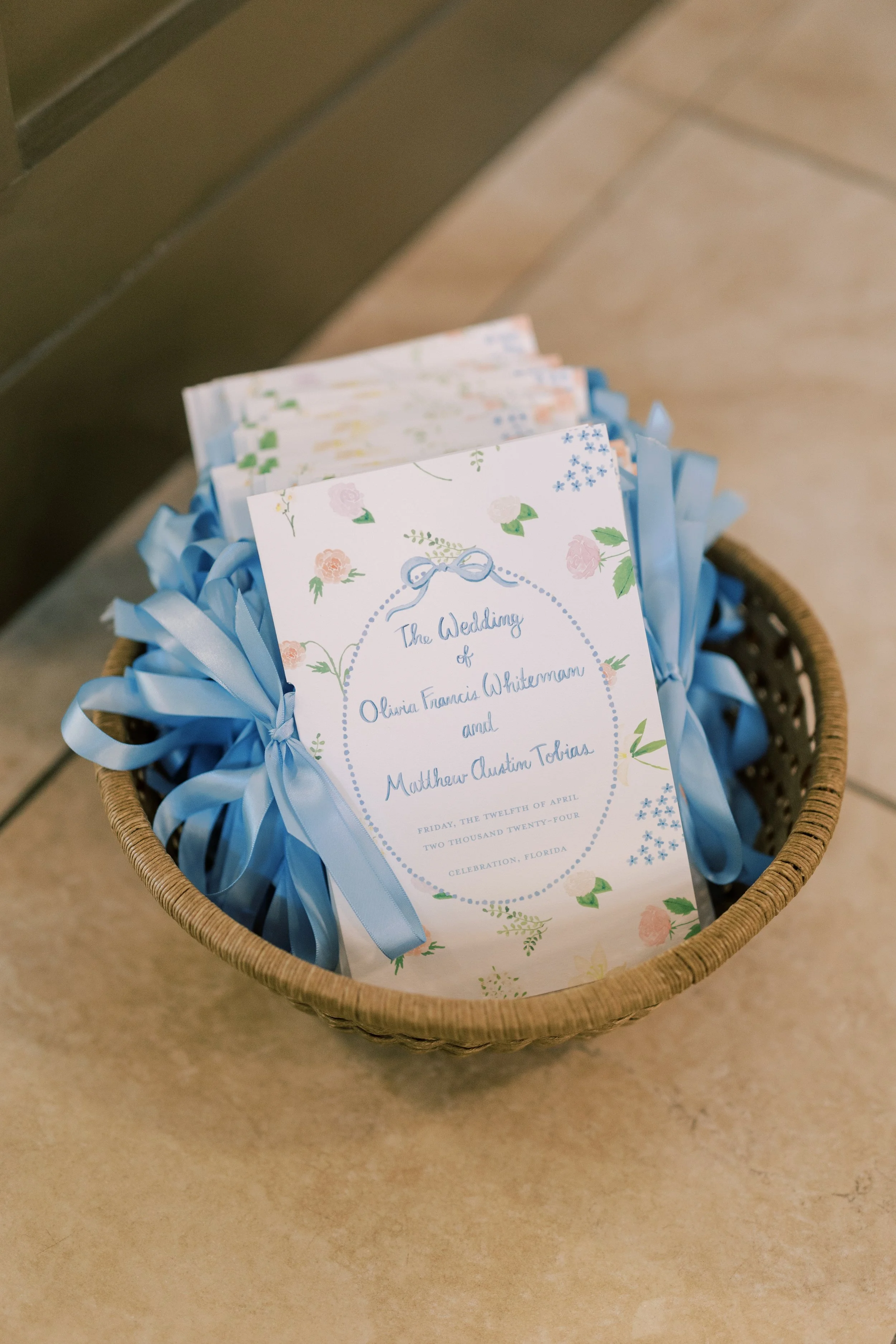 Wedding program for Olivia Francis Whiteman and Matthew Austin Tobias in a wicker basket with blue ribbon