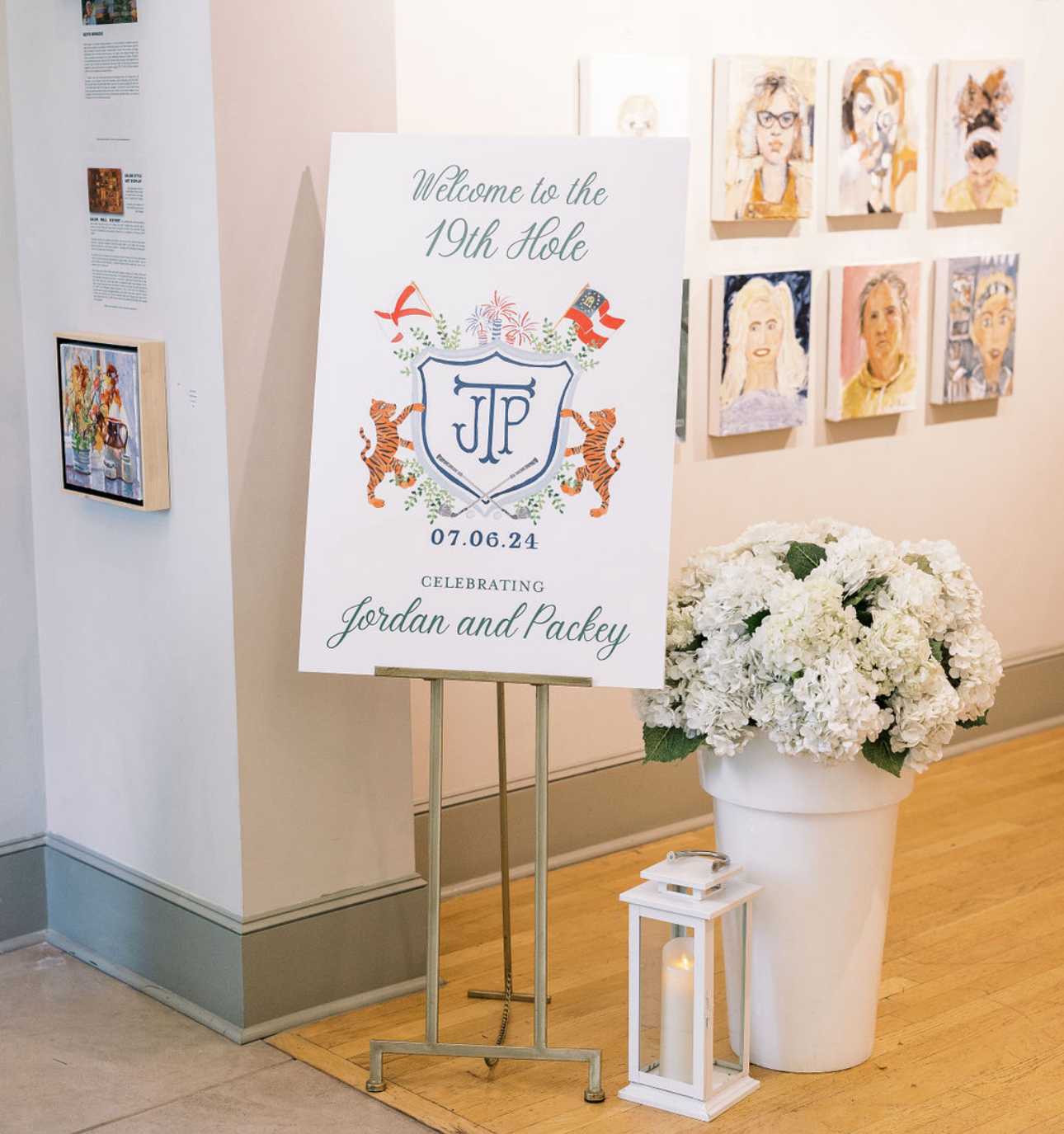 Wedding reception sign welcoming guests to the 19th Hole, celebrating Jordan and Packey on July 6, 2024. The sign is decorated with images of fireworks, two tigers, and flags. Next to the sign is a large white vase filled with white hydrangeas and a 